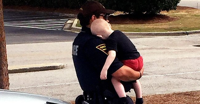 Un officier de police console un bébé d'un an abandonné par ses parents suite à une overdose d'héroïne. | Photo : facebook.com/Fayetteville.Police