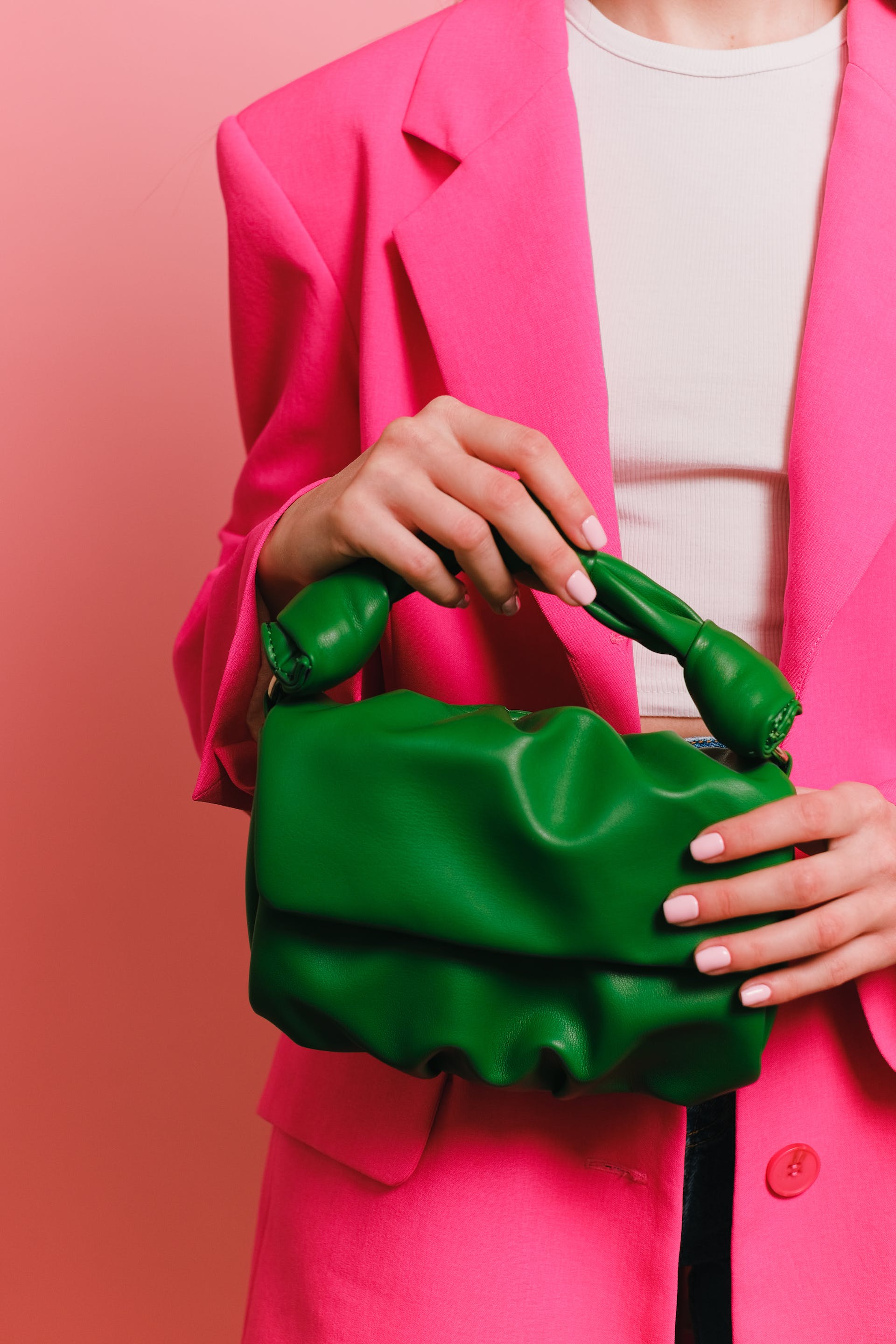 Femme en blazer rose tenant un sac à main vert | Source : Pexels