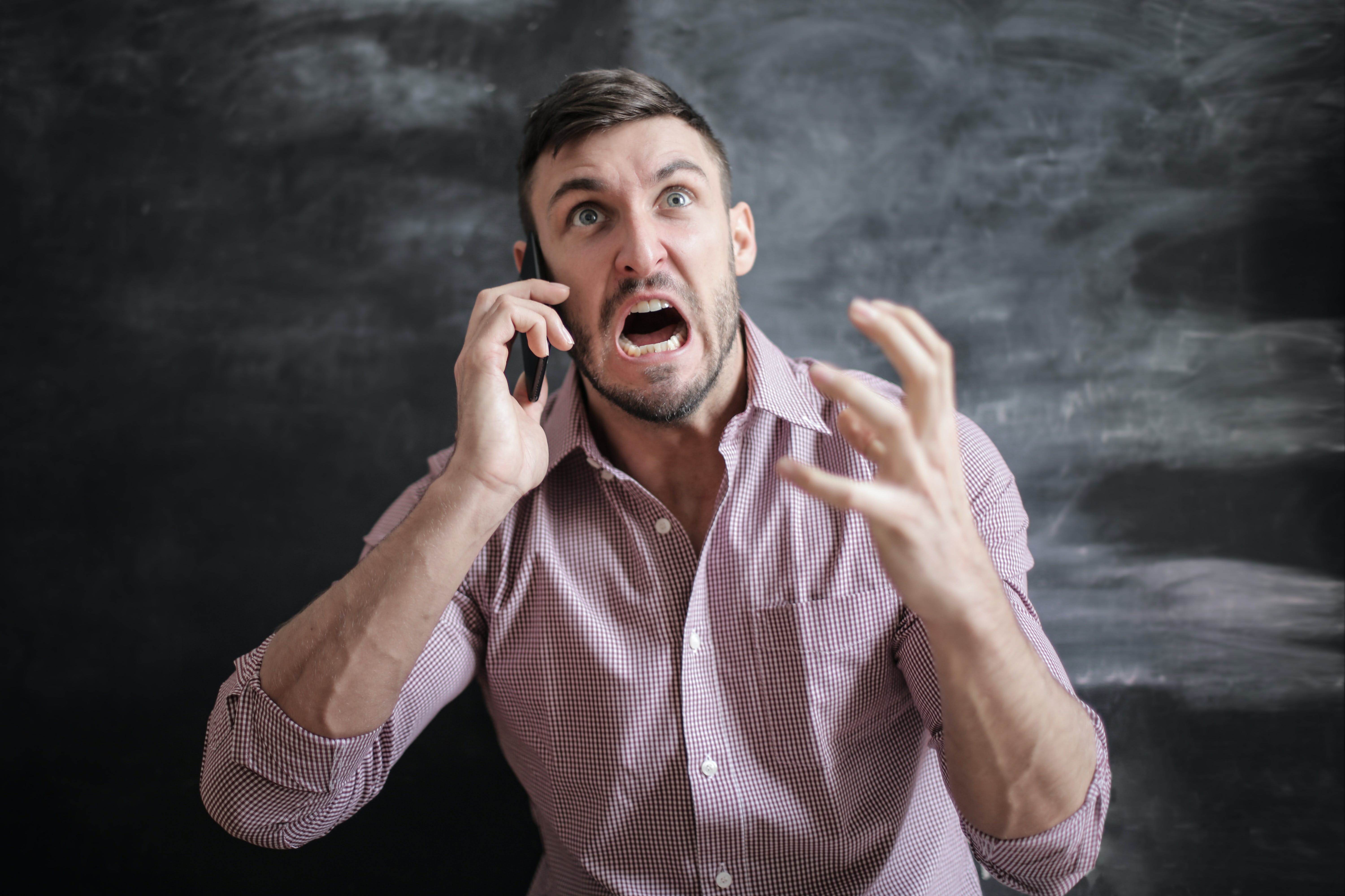 Un homme crie en faisant des gestes de colère pendant un appel téléphonique | Source : Pexels