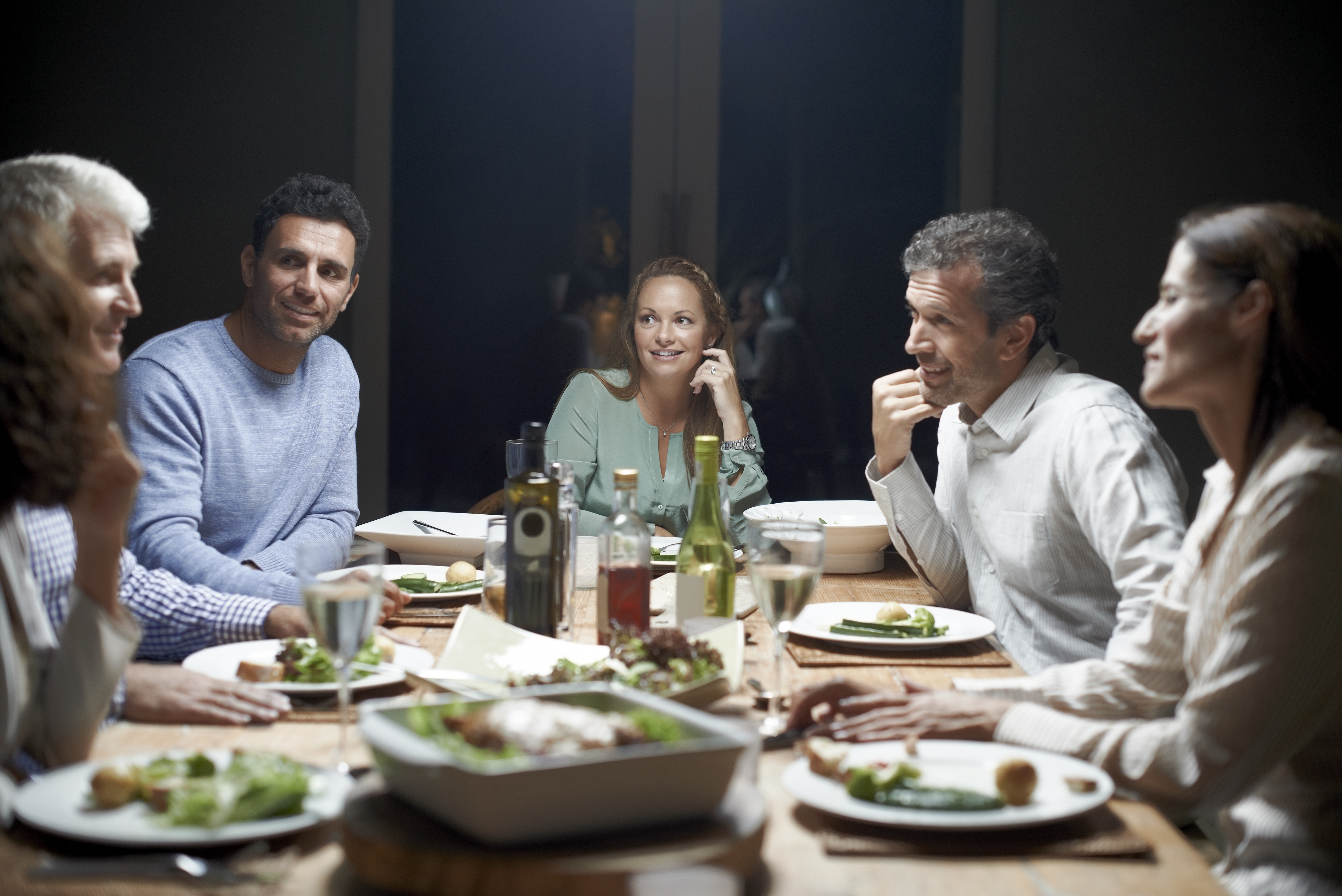 Des amis communiquent tout en dînant à table | Source : Getty Images
