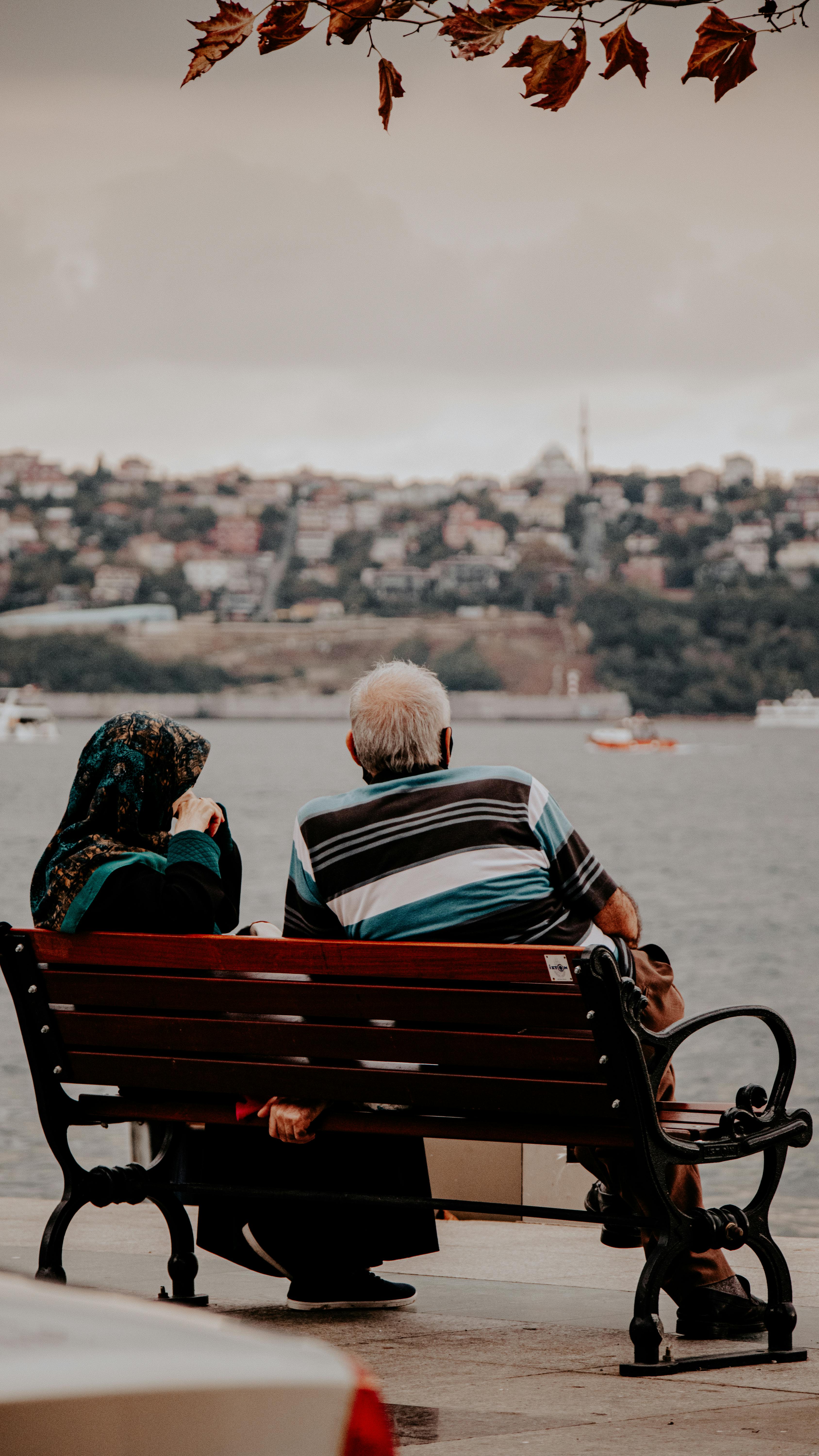 Un couple d'âge moyen assis sur un banc surplombant l'eau | Source : Pexels