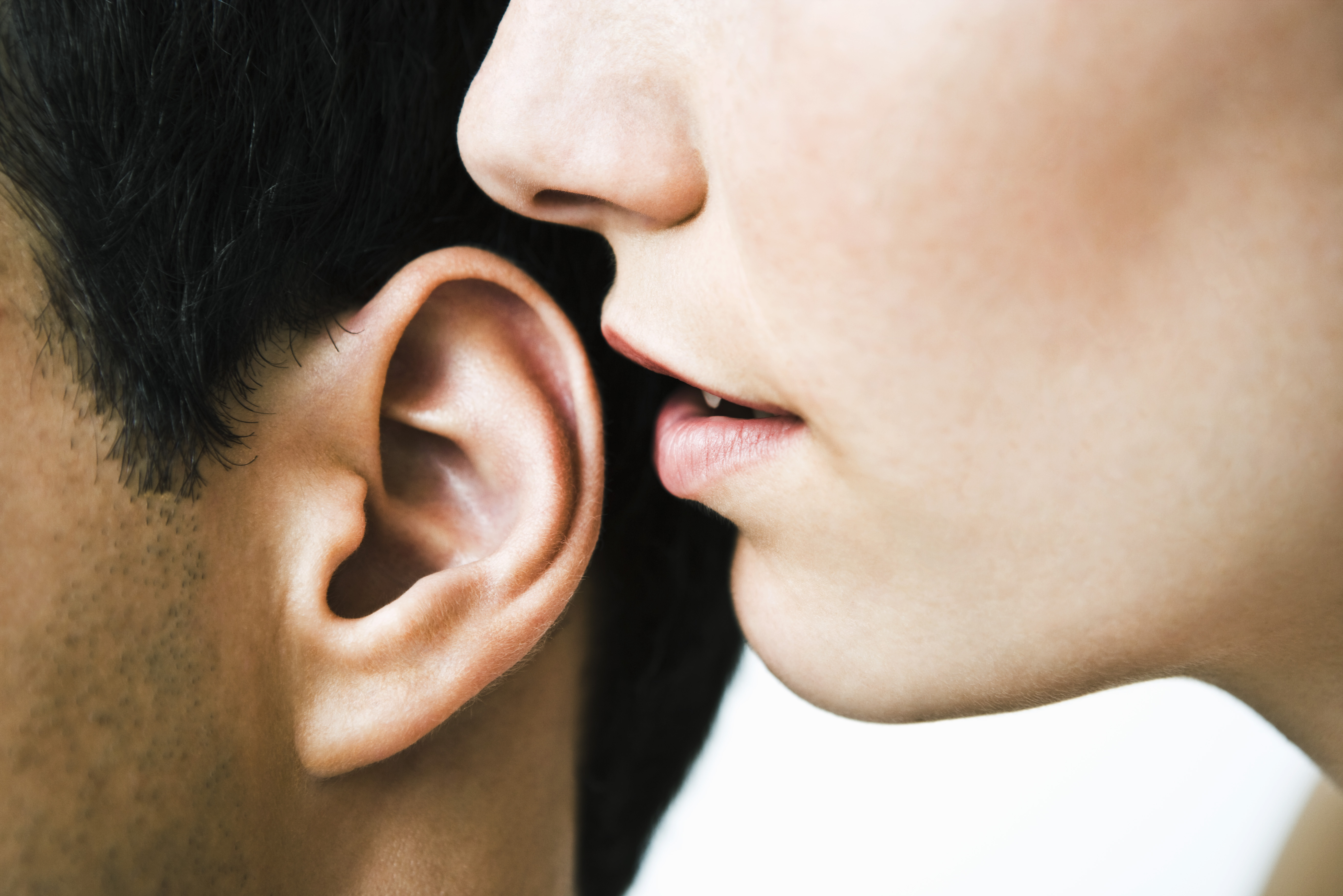 Femme chuchotant à l'oreille d'un homme, gros plan | Source : Getty Images