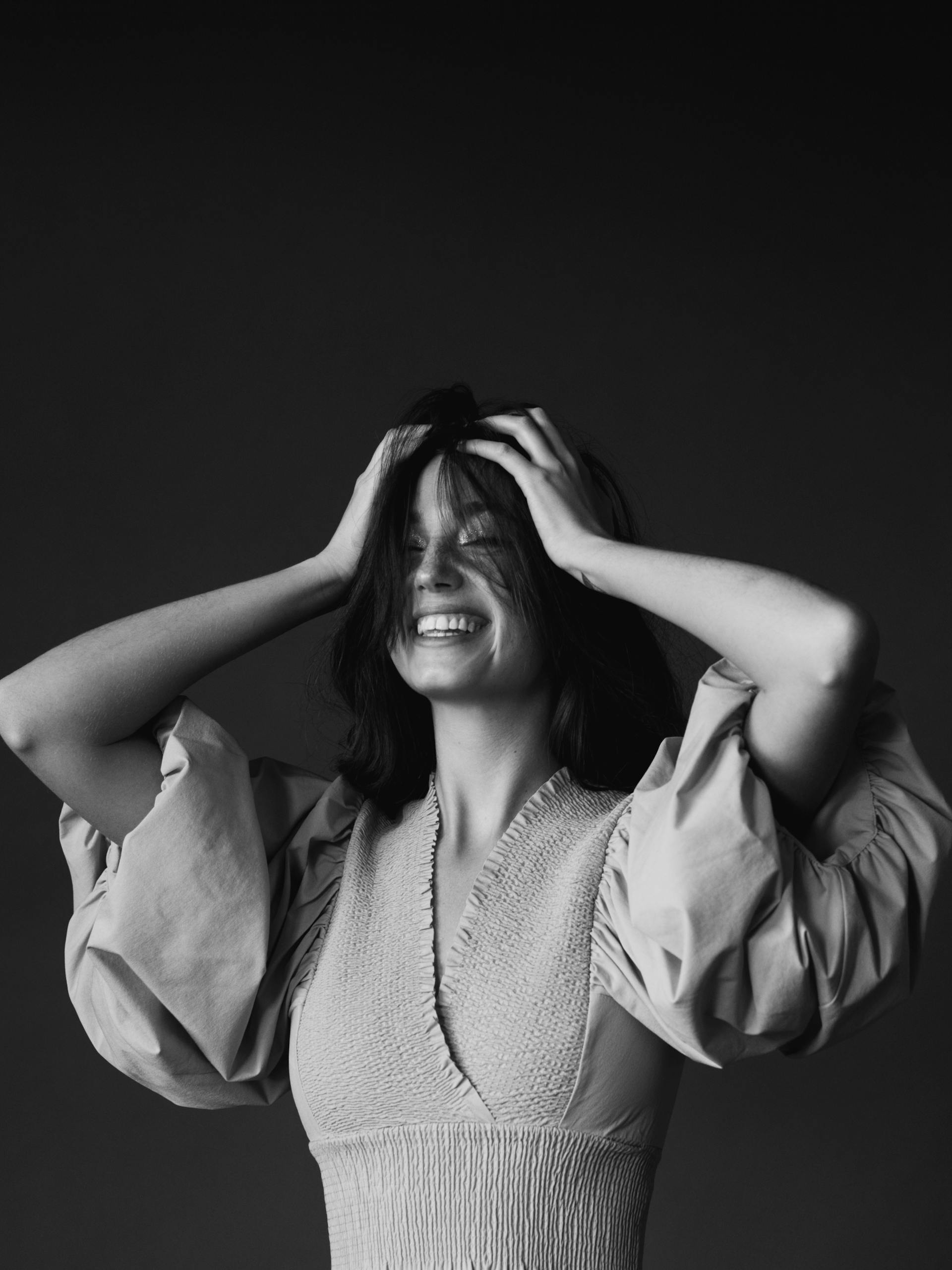 Photo en niveaux de gris d'une femme qui rit en se couvrant la tête avec les deux mains | Source : Pexels