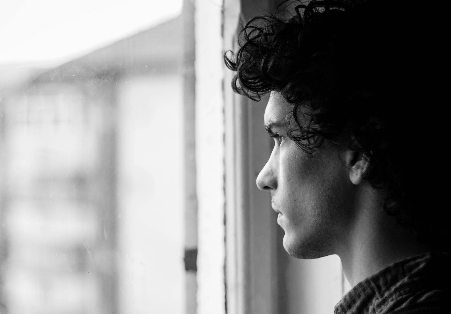 Un jeune homme qui regarde par la fenêtre | Source : Pexels