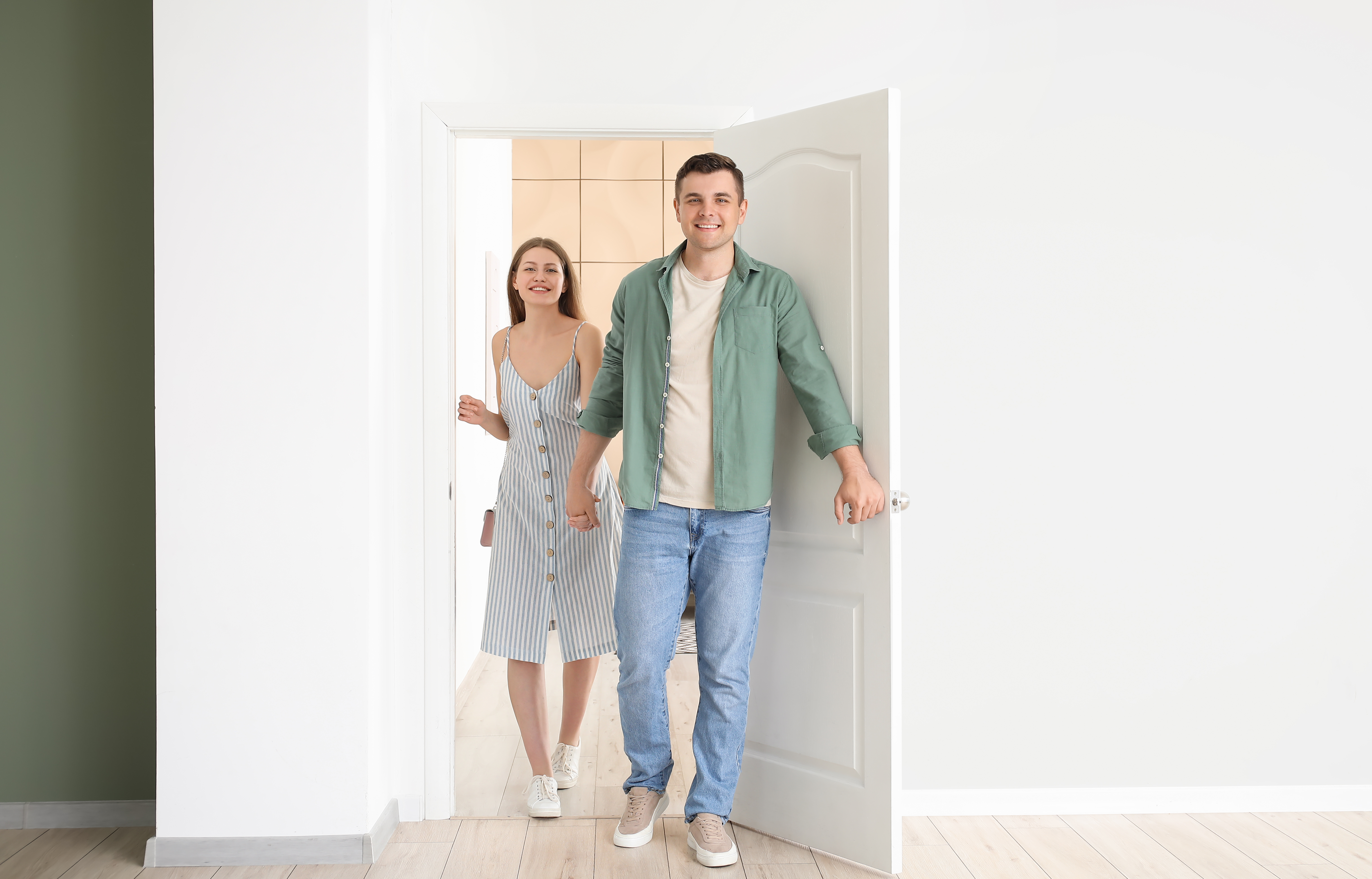 Pareja feliz abriendo la puerta y entrando en la habitación | Fuente: Shutterstock.com