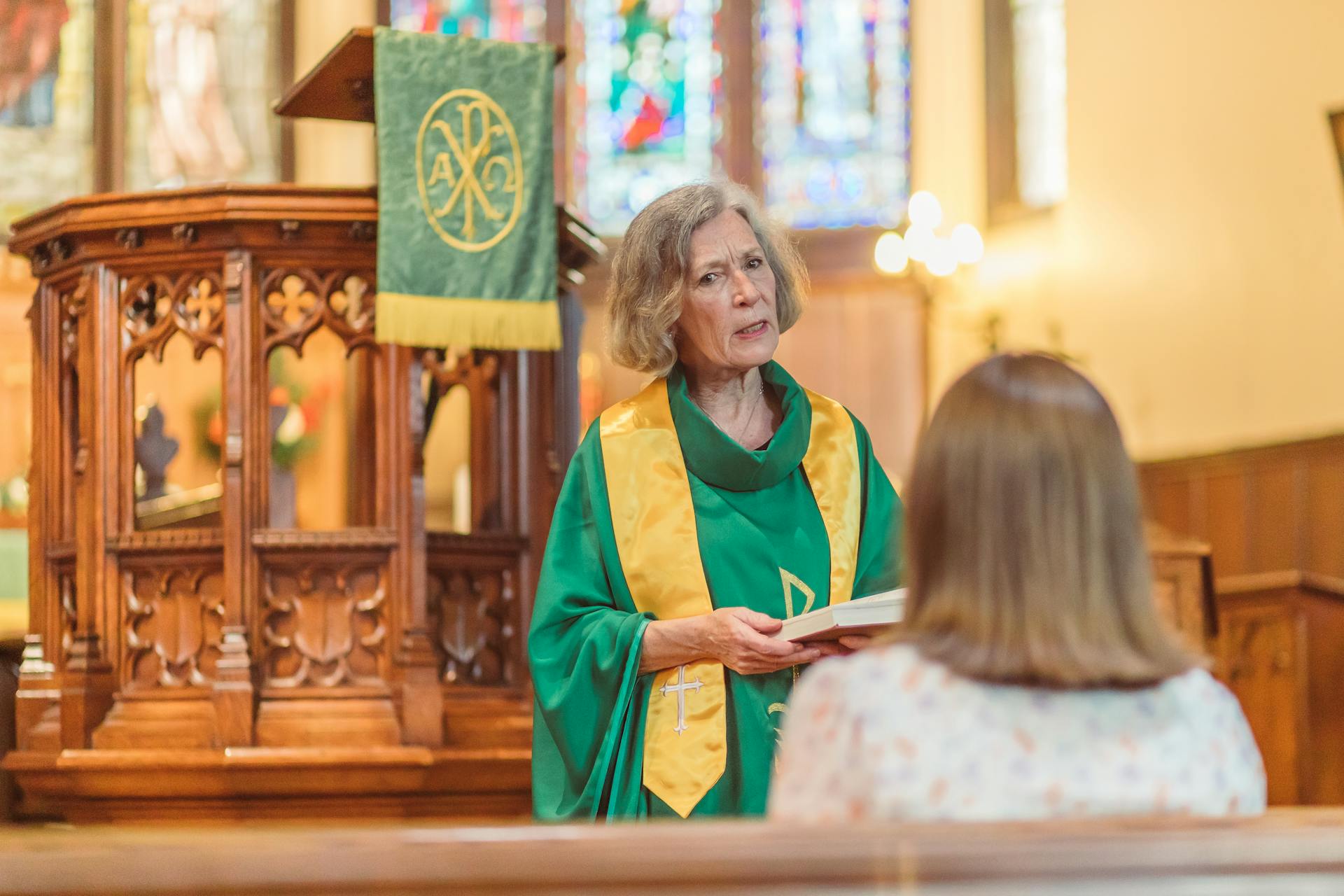 Une femme plus âgée tenant un livre et discutant avec une jeune femme dans l'église | Source : Pexels