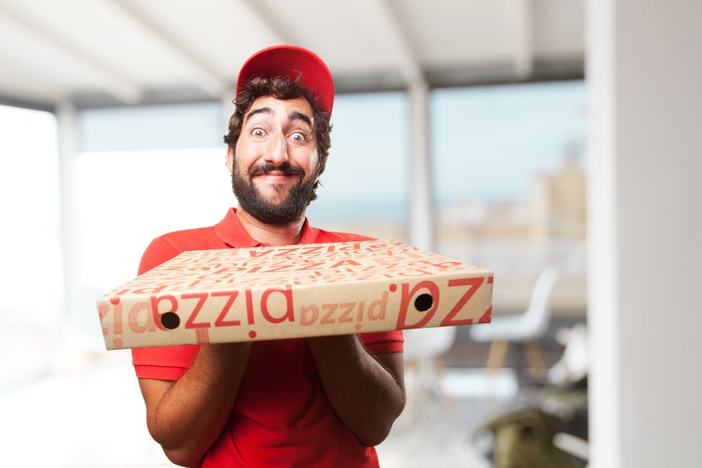 Livreur de pizza aux expressions faciales hilarantes. | Shutterstock