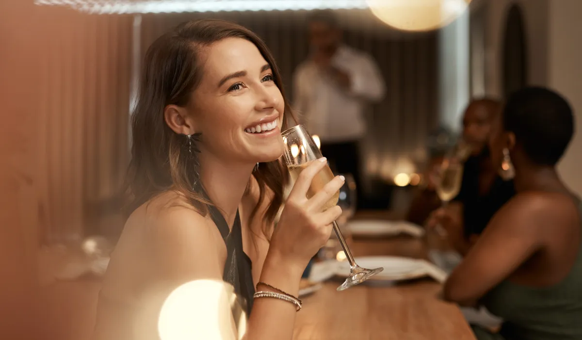 Une femme tenant une coupe de champagne dans un restaurant | Source : Shutterstock