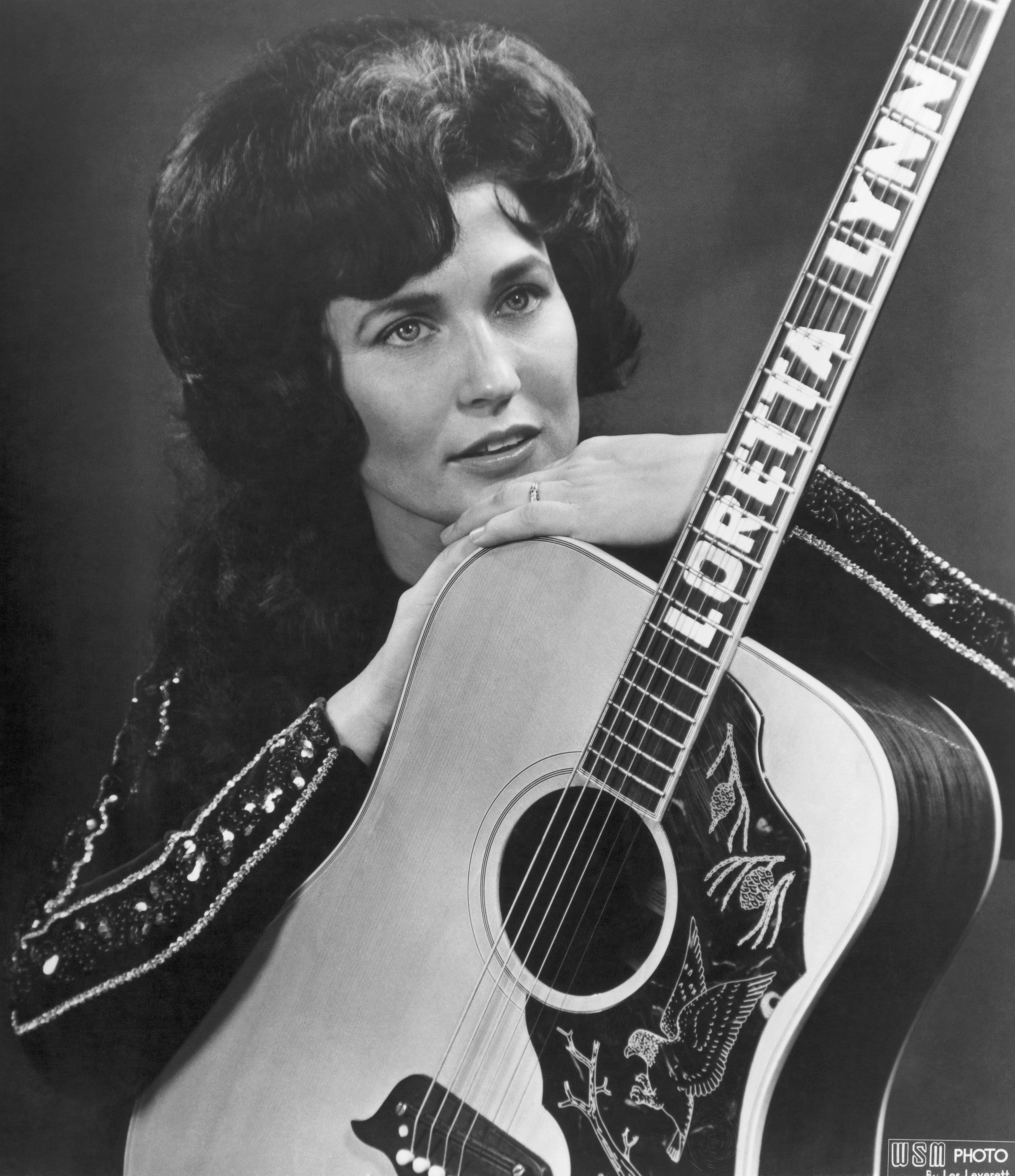 Loretta Lynn pose pour un portrait en tenant une guitare sur laquelle son nom est écrit en toutes lettres, à Nashville, Tennessee, en 1961. | Source : Getty Images