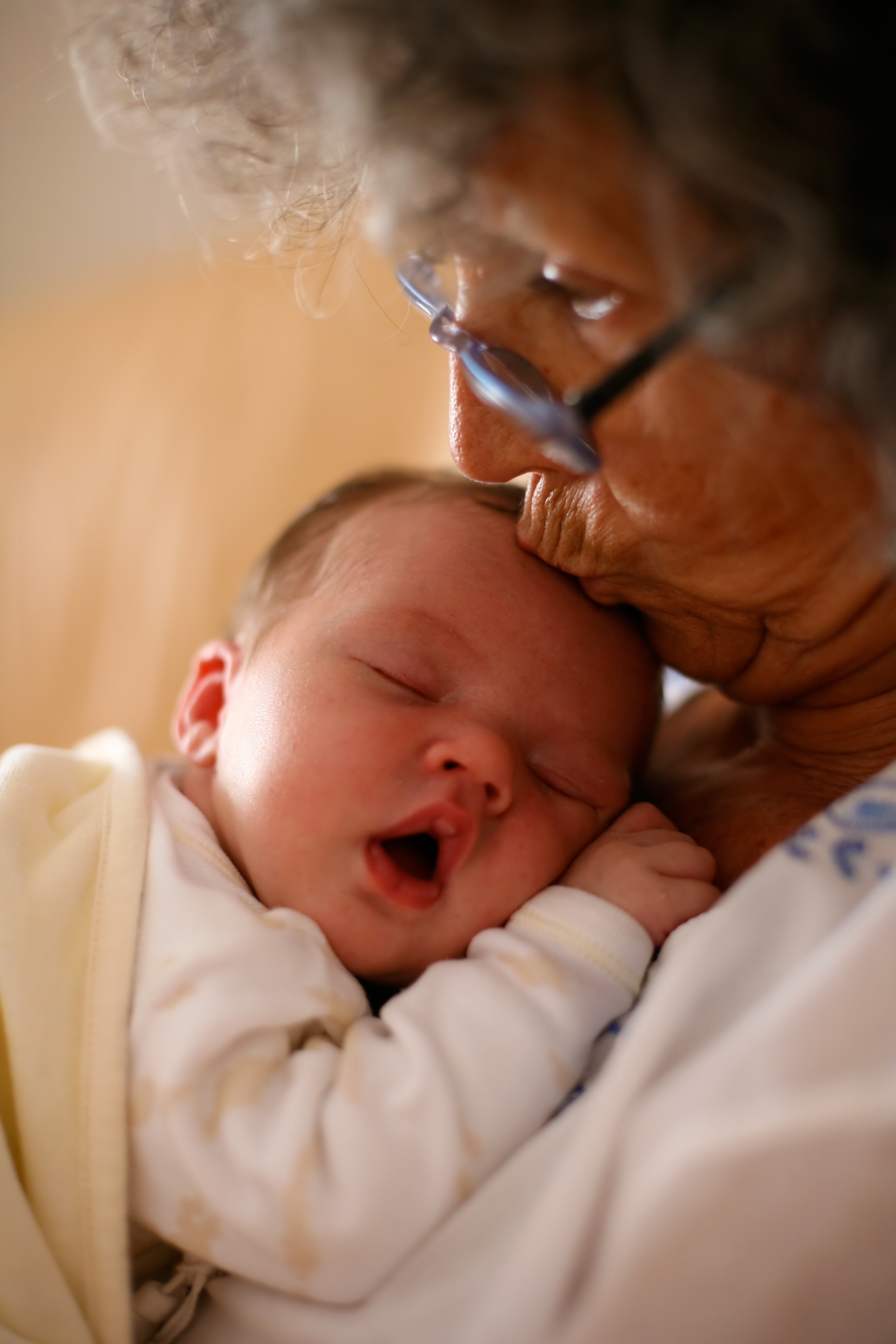 Abuela sujetando a un bebé y dándole un beso en la cabeza. | Fuente: Shutterstock