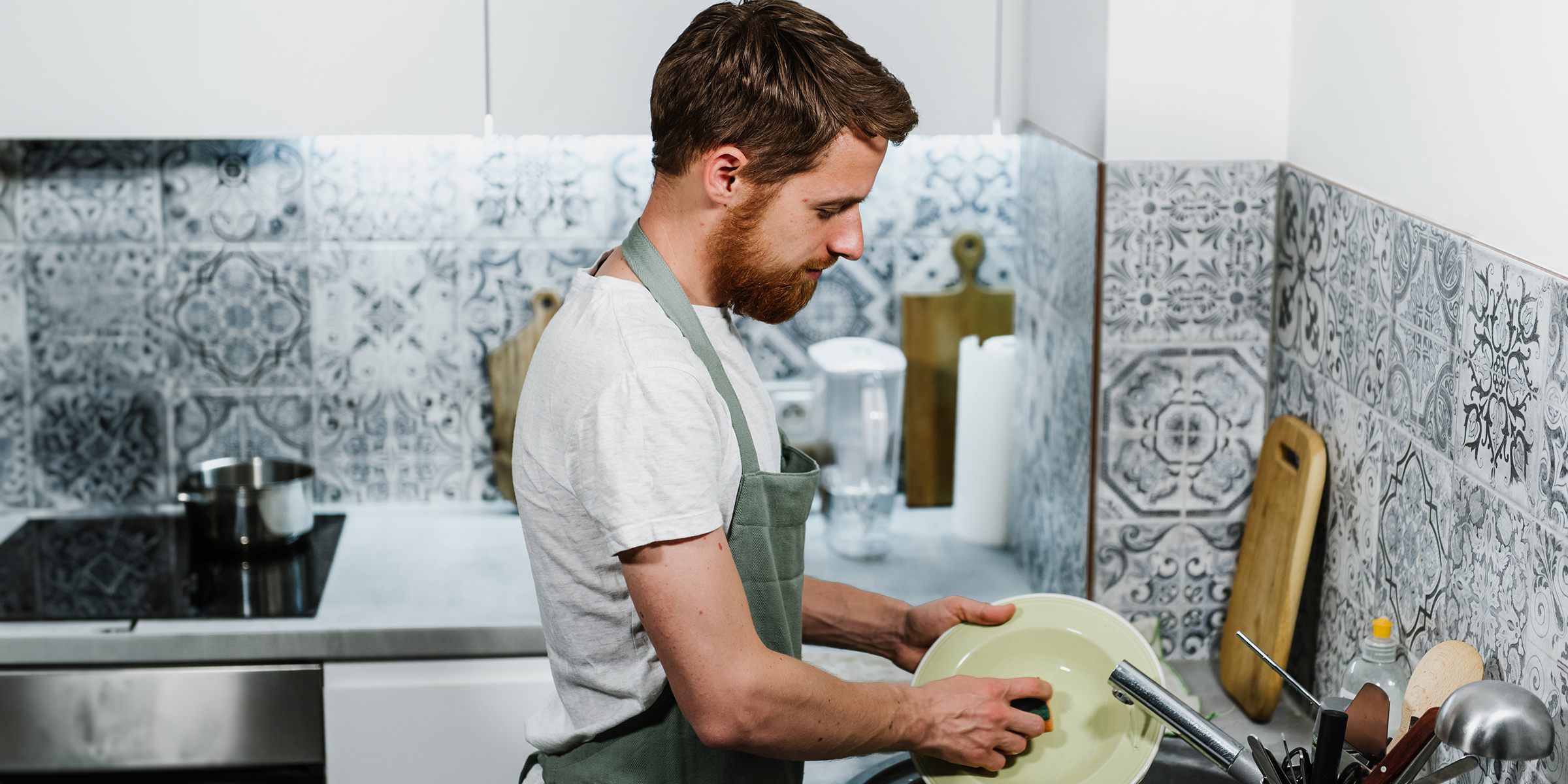 Un homme qui fait la vaisselle dans la cuisine | Source : Shutterstock