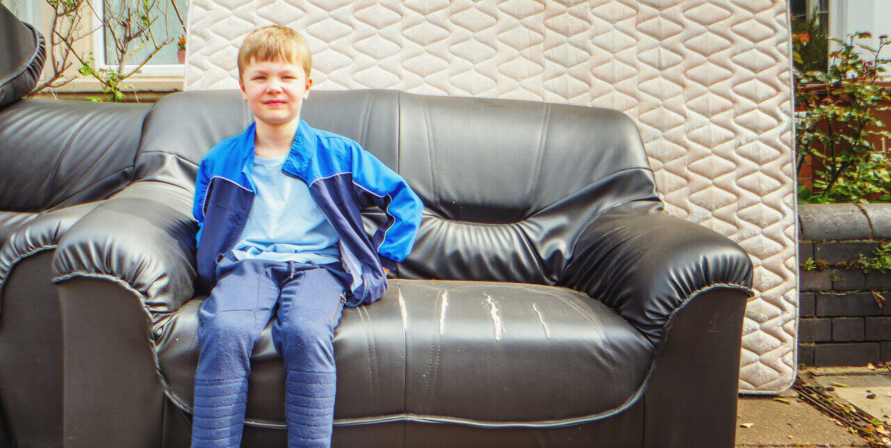 Menino sentado em um sofá | Fonte: Shutterstock