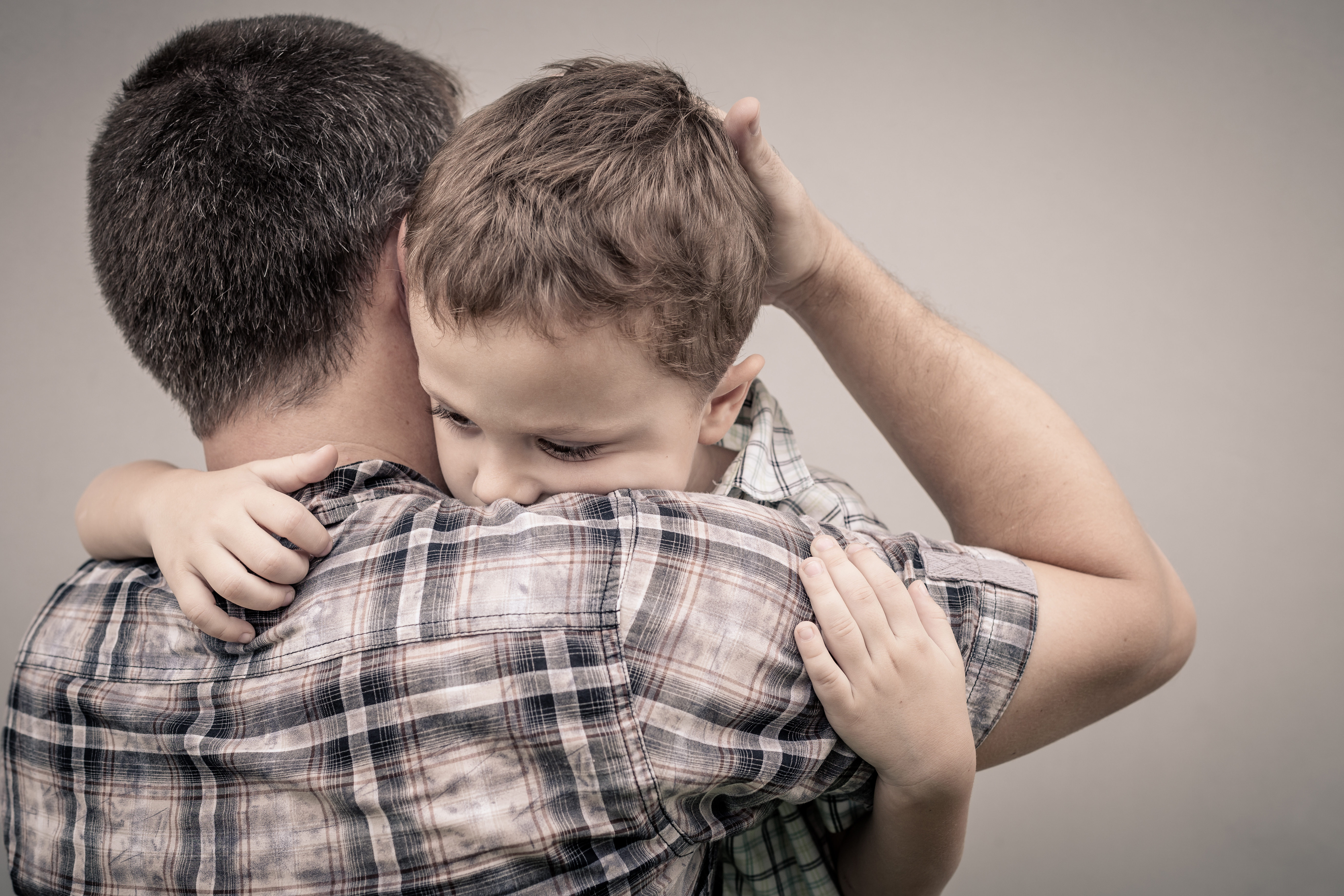 Un père serrant dans ses bras son fils à l'air triste | Source : Shutterstock
