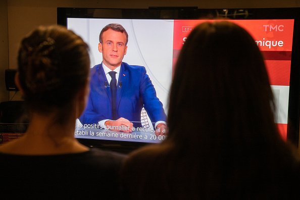 Des citoyennes regardent le discours du résident Macron à la télévision. | Photo : Getty Images