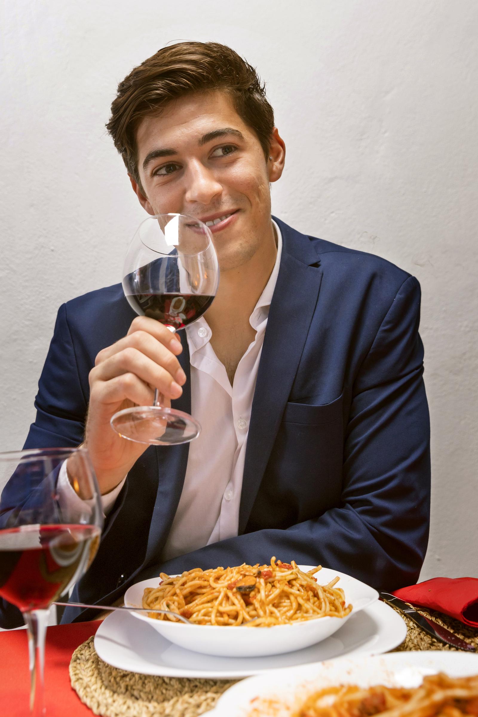 Un homme souriant à une table de dîner | Source : Freepik