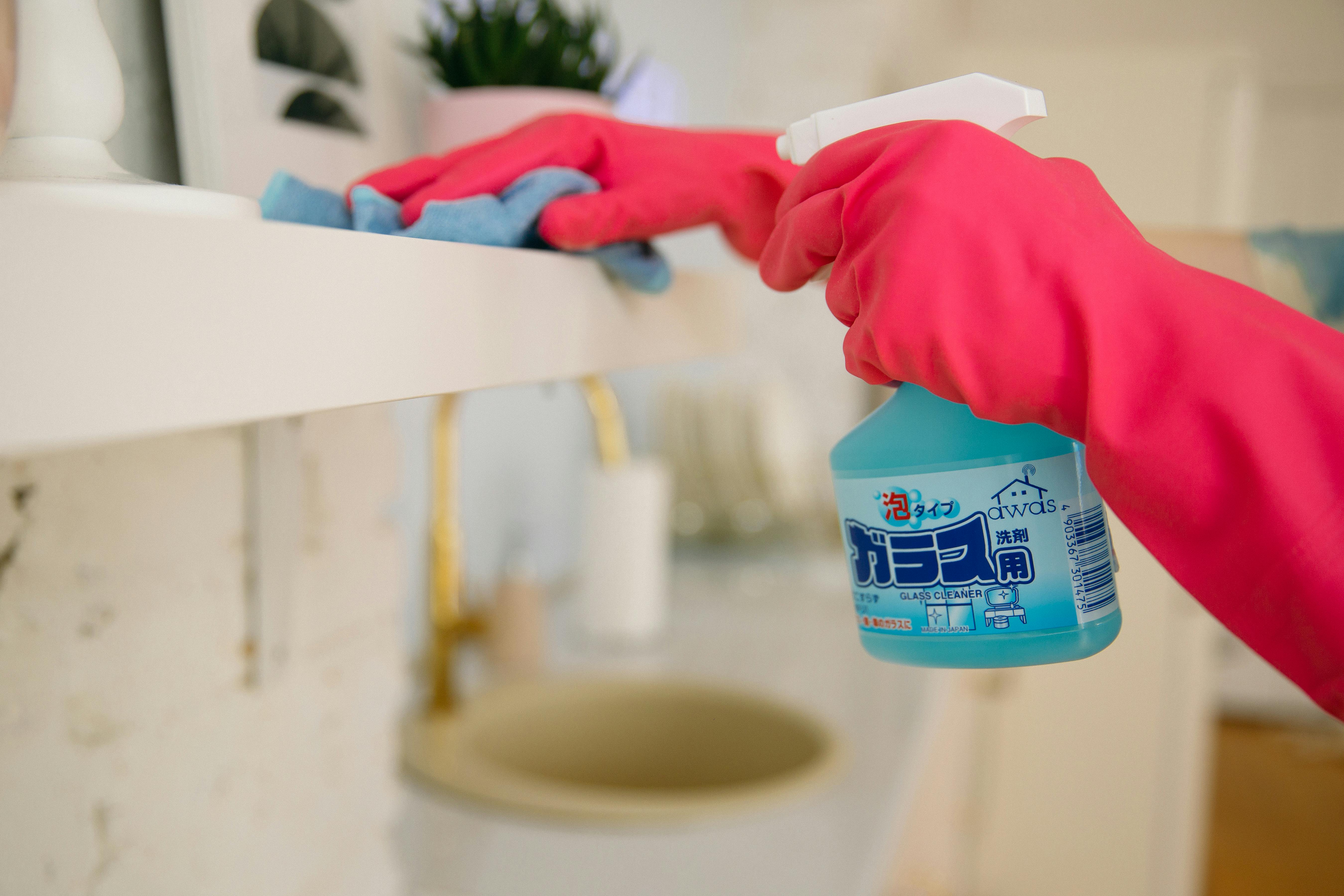 Une personne avec des gants tenant un flacon pulvérisateur de nettoyant pour vitres | Source : Pexels