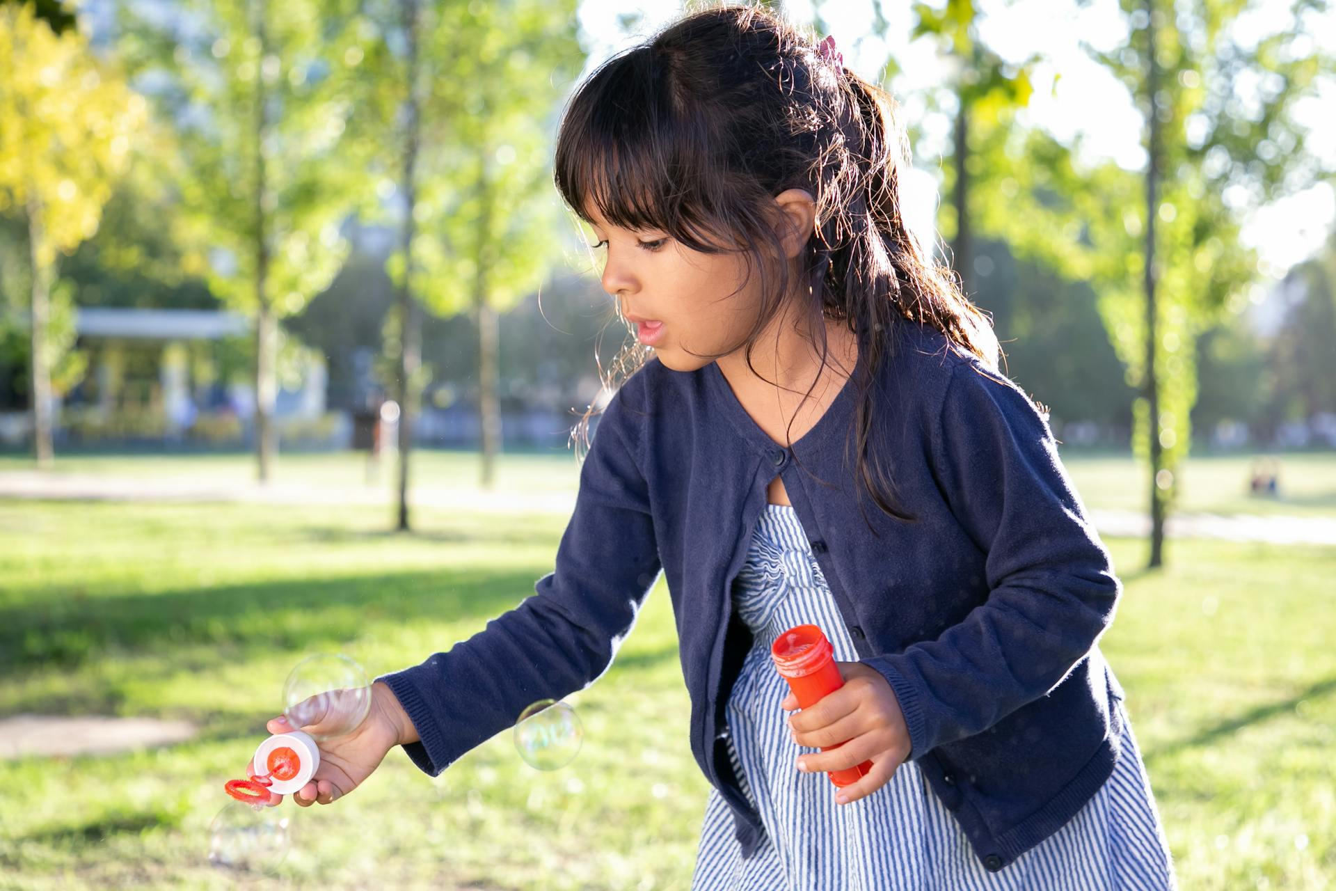 Une fille qui fait des bulles dans un parc | Source : Pexels