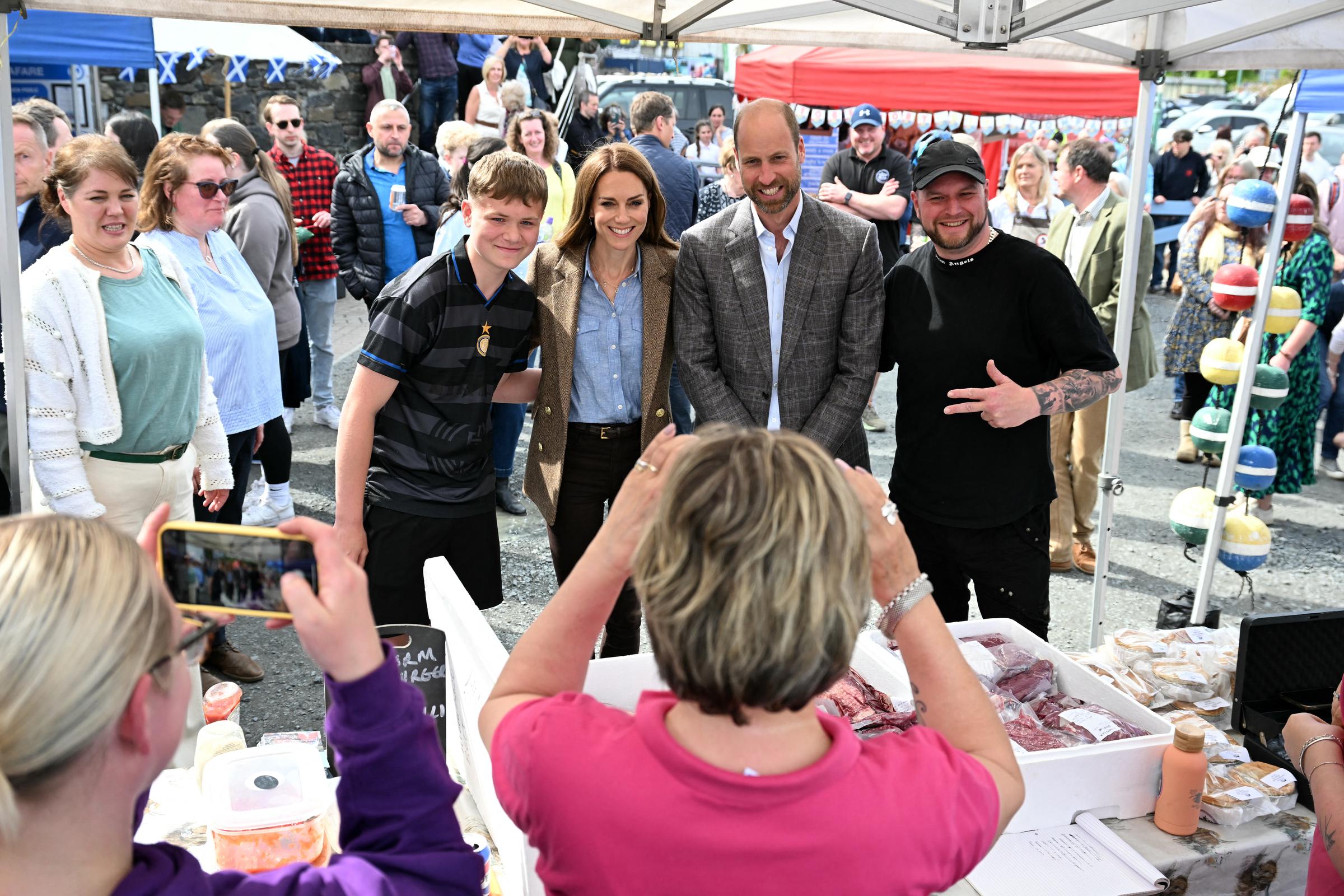 William et Catherine posent pour une photo joyeuse avec des habitants sur un stand du marché de Tobermory. Le couple a visité le marché pour mettre en lumière l'entreprenariat communautaire et les initiatives des petites entreprises à travers l'île.