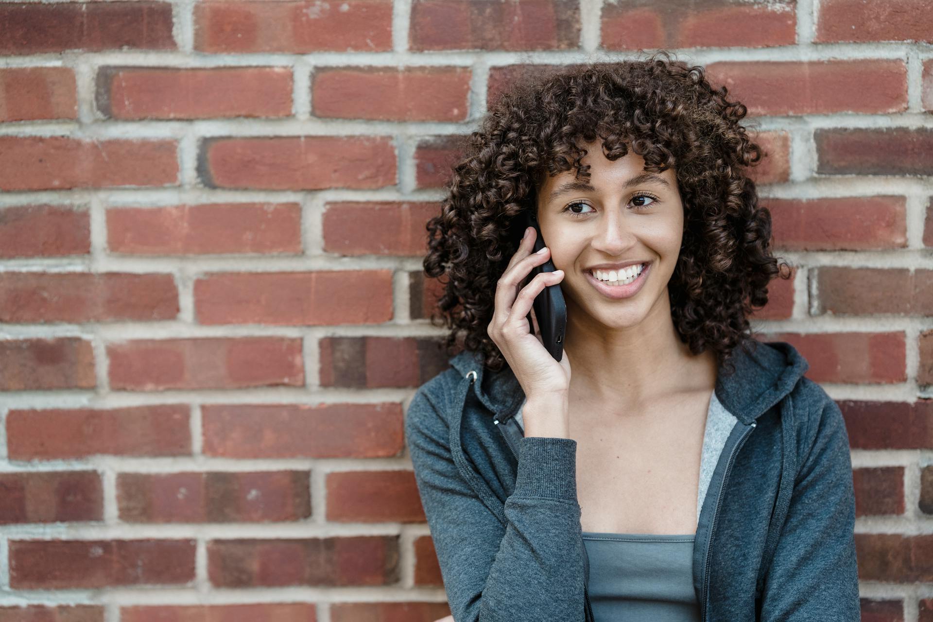 Une femme qui sourit pendant un appel téléphonique | Source : Pexels