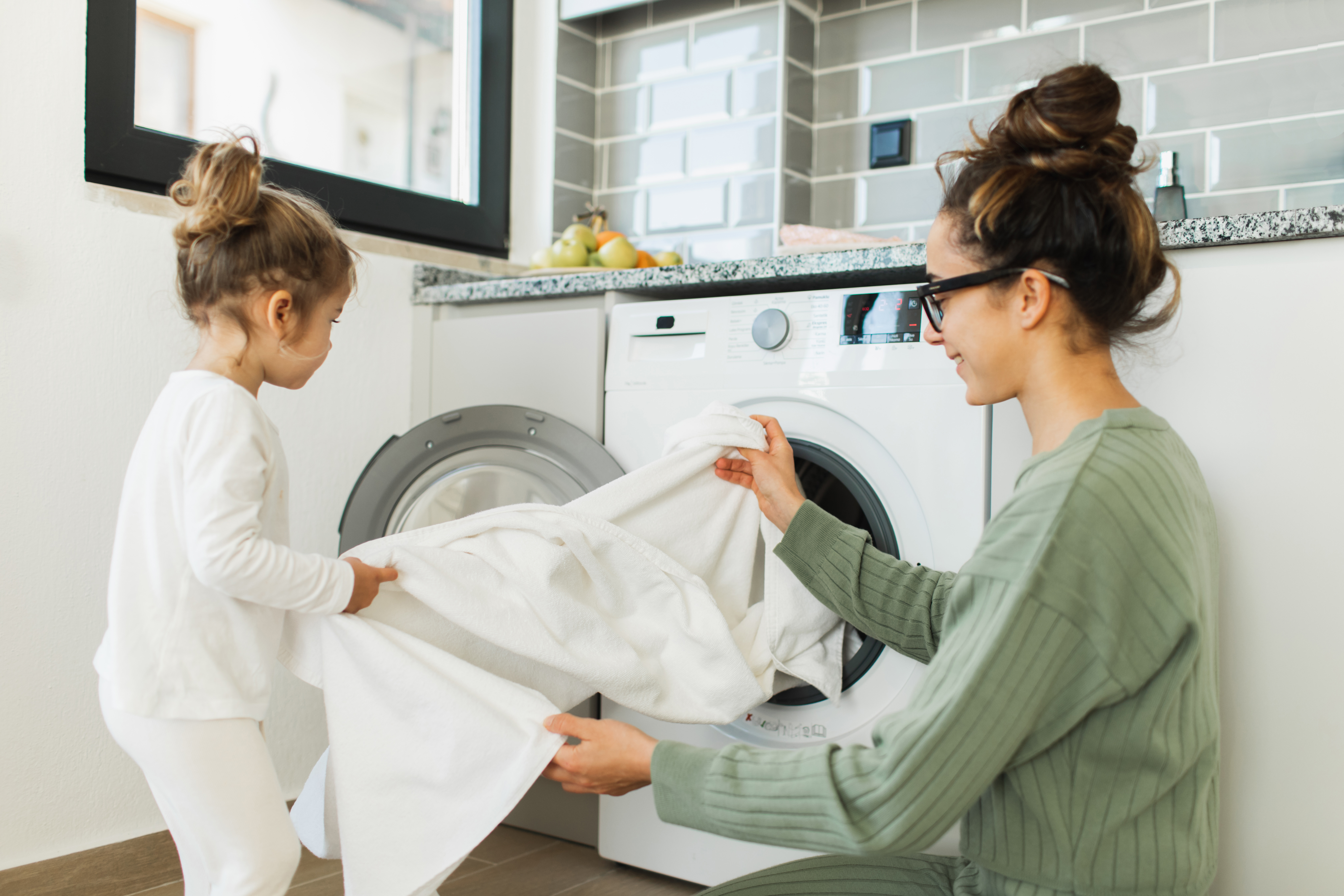 Une mère et sa petite fille qui chargent une machine à laver | Source : Getty Images