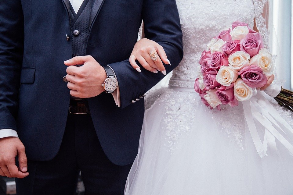 Homme et femme en tenue de mariage avec les bras en boucle. | Photo : Pixabay