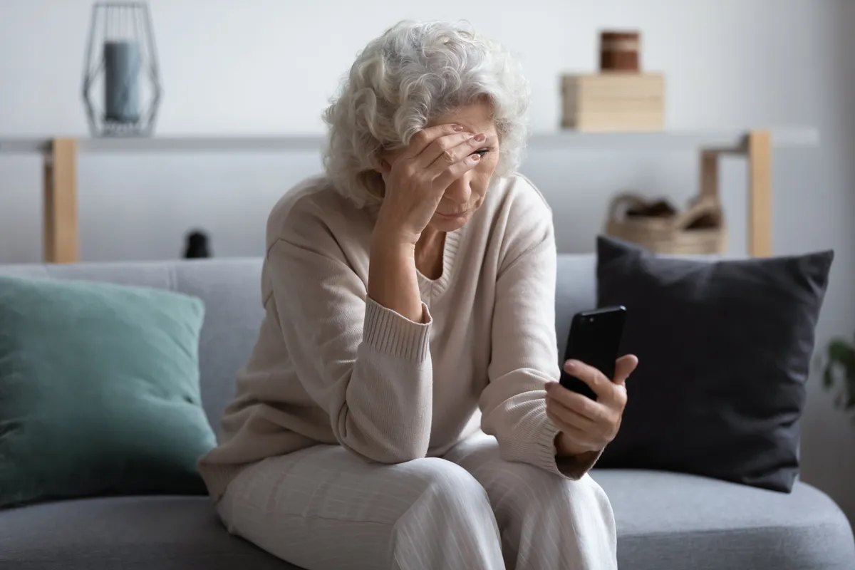 Une femme âgée malheureuse qui regarde l'écran de son téléphone | Source : Shutterstock