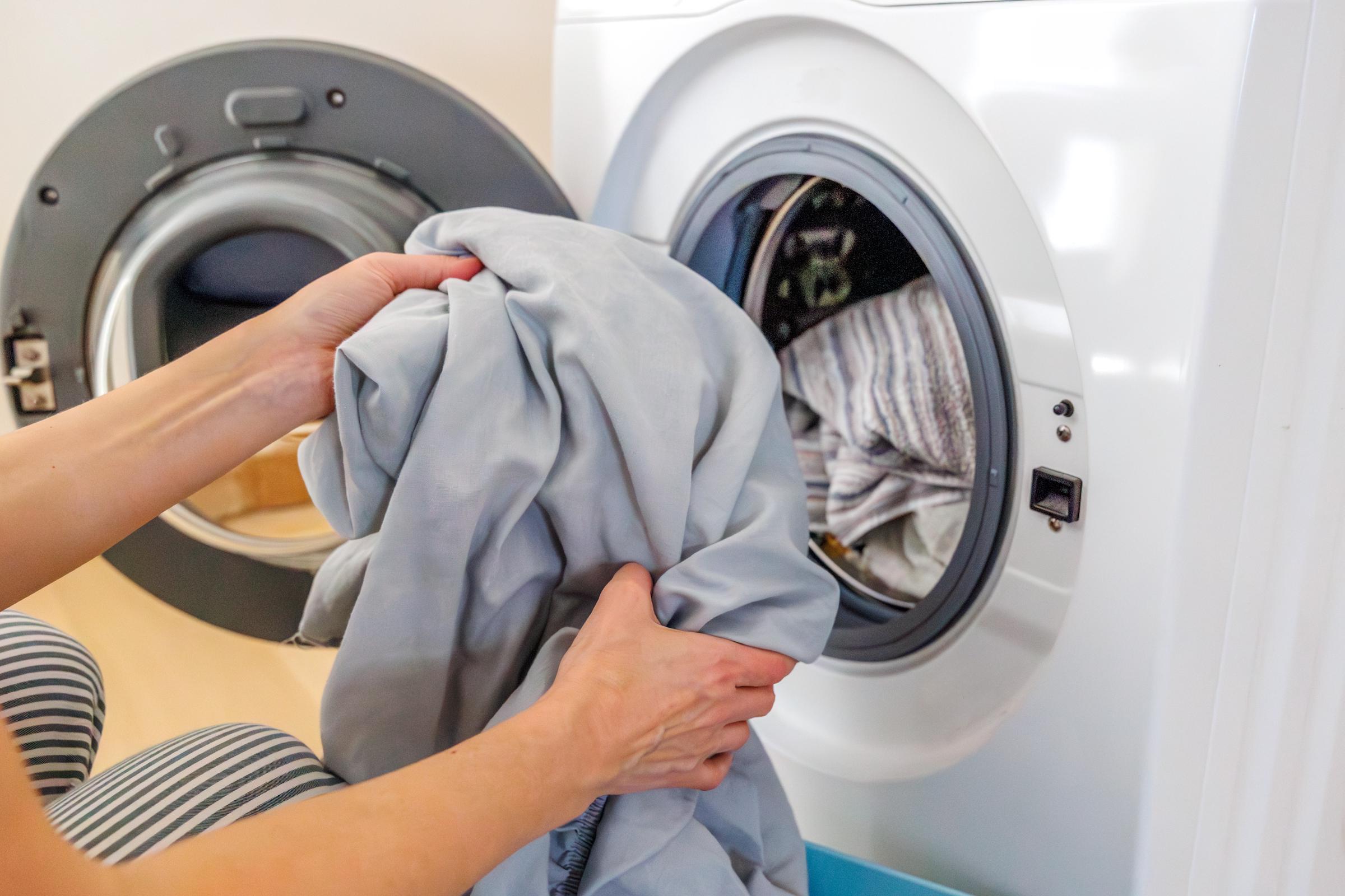 Une personne qui met du linge dans la machine à laver | Source : Getty Images