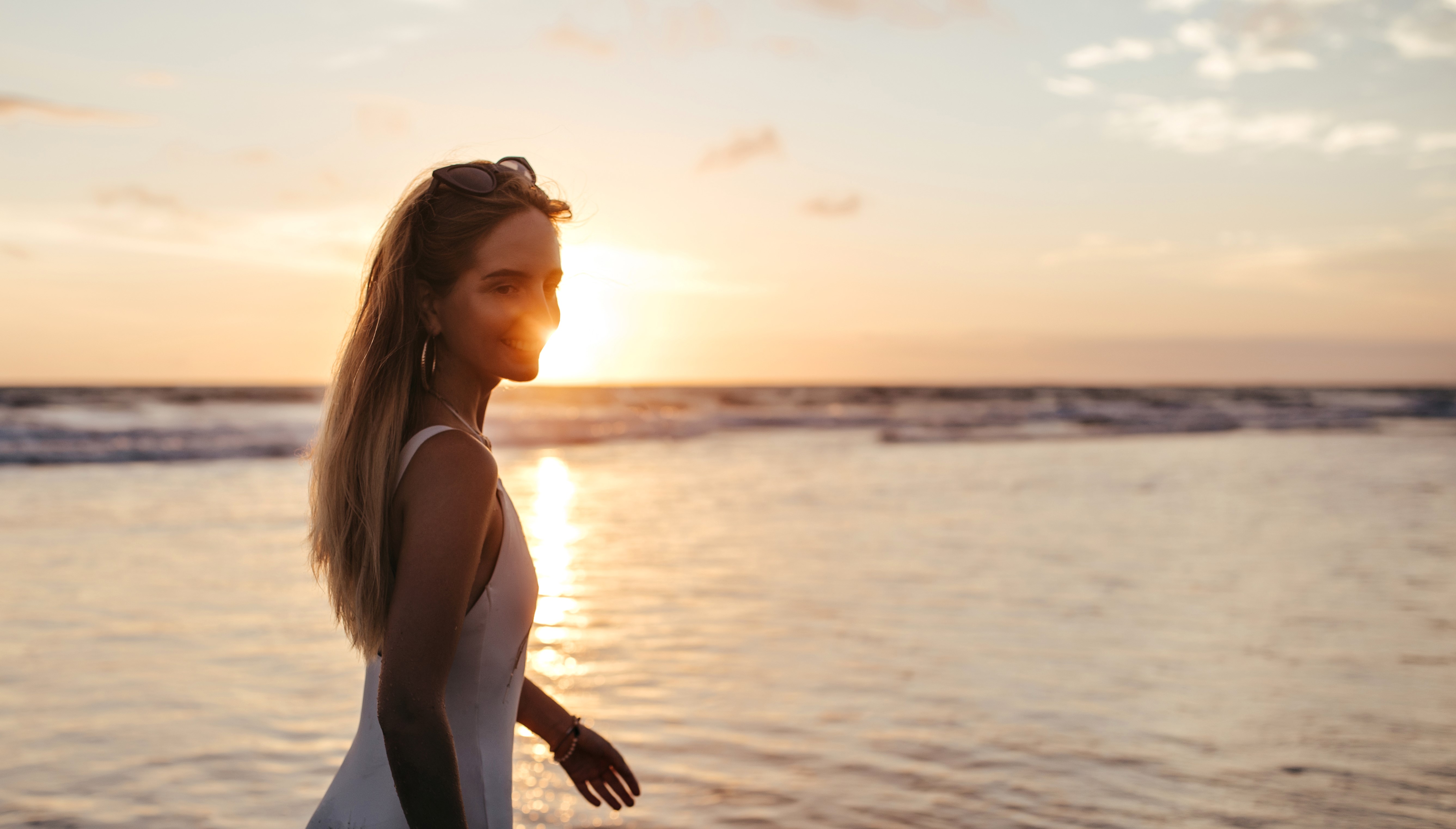 Une femme souriante en maillot de bain blanc près de la mer | Source : Freepik