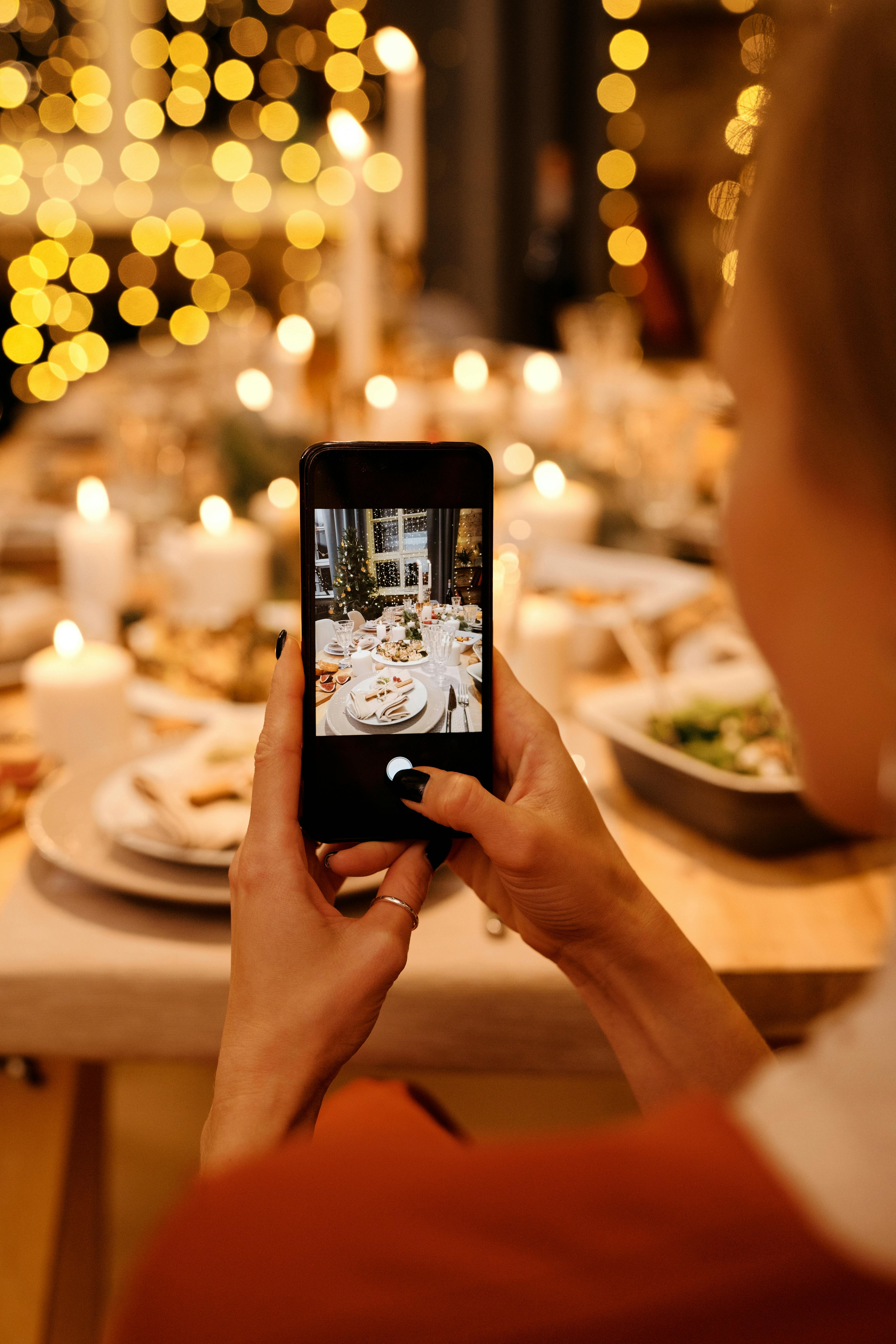 Une main tenant un téléphone portable et prenant une photo d'un service de table | Source : Pexels