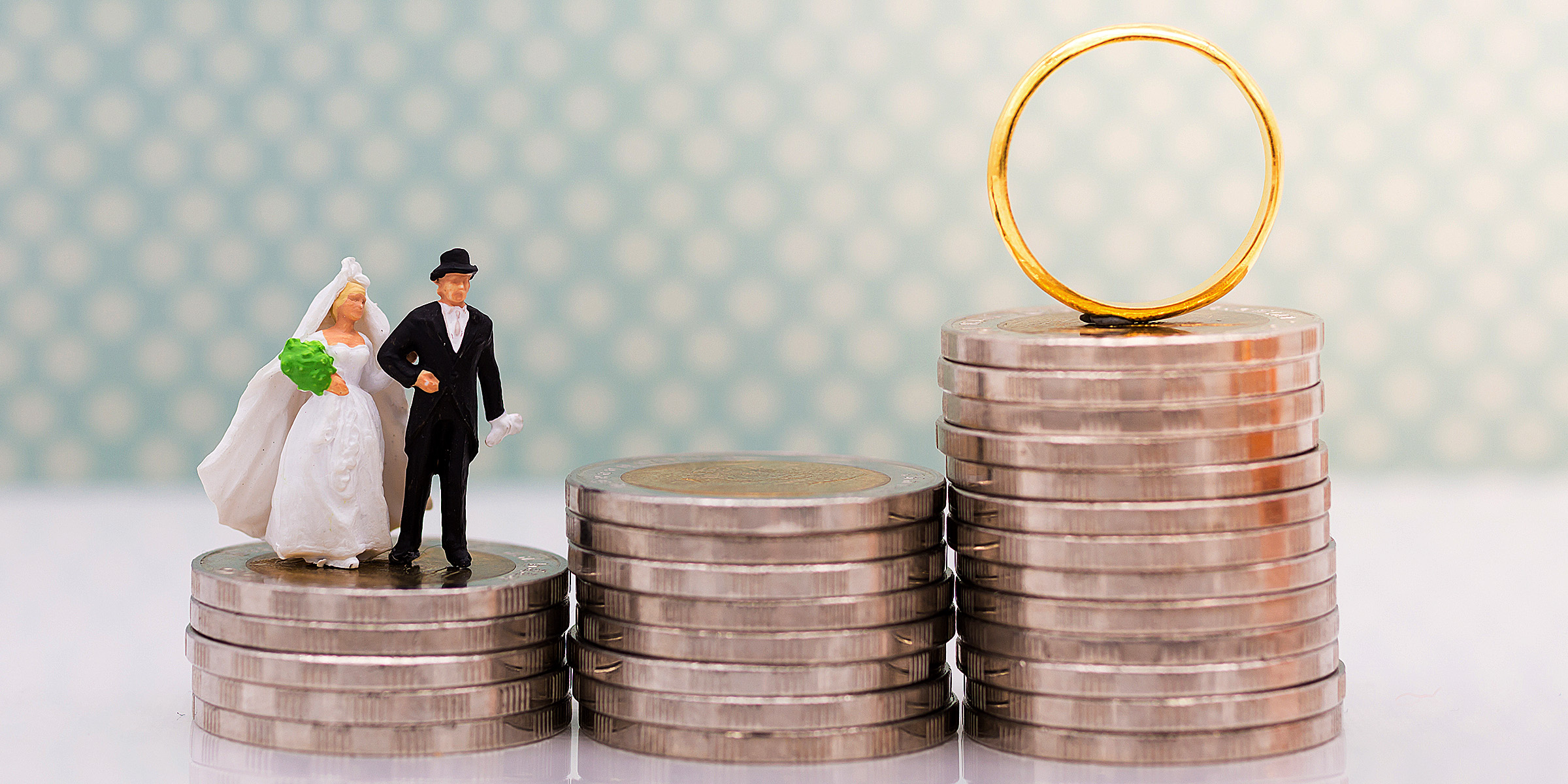 Mariés miniatures debout sur une pile de pièces de monnaie | Source : Shutterstock