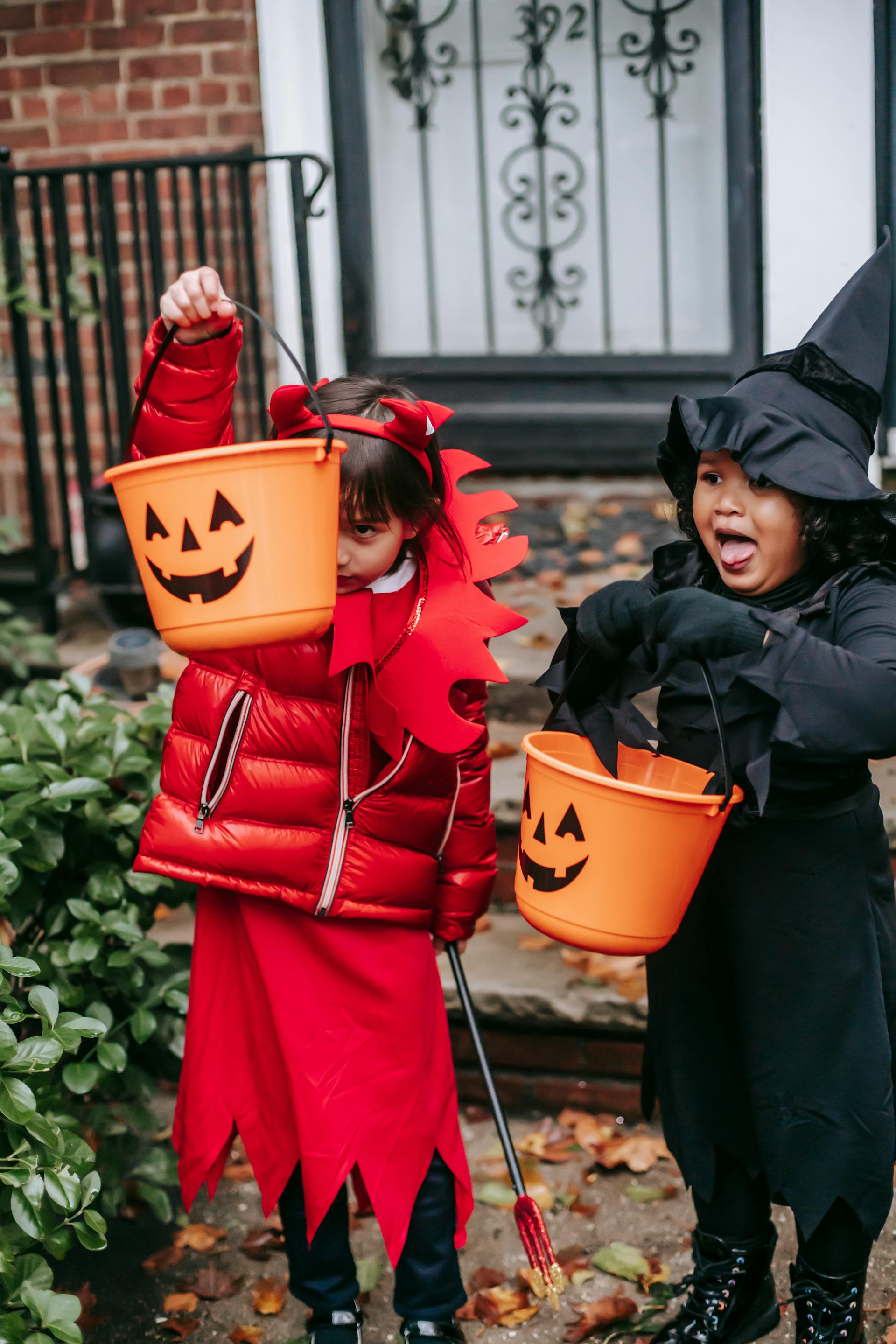 Des enfants font des tours de magie en costume d'Halloween près de l'entrée d'une maison | Source : Pexels