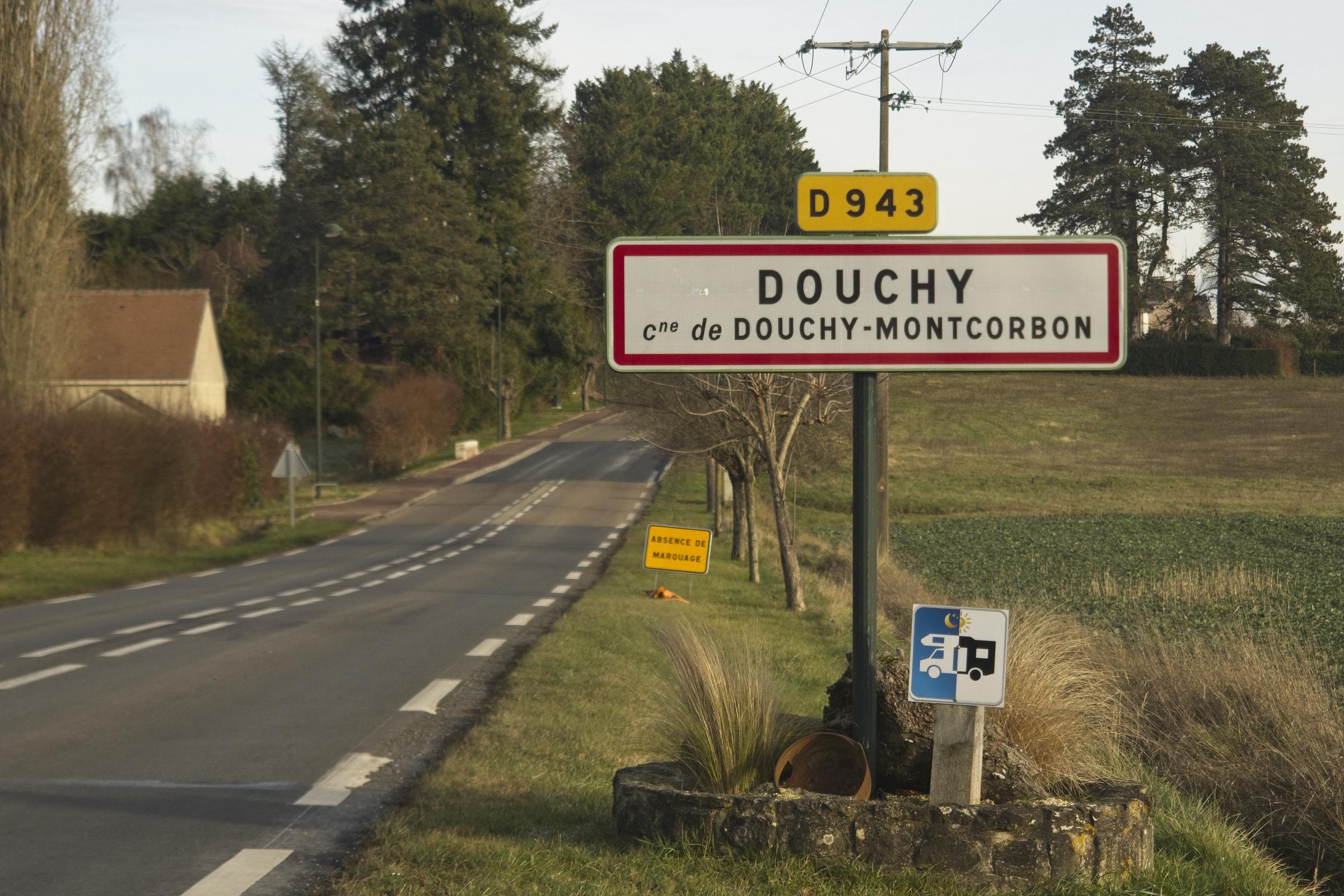 Cette photographie prise le 16 janvier 2024, montre le panneau d'entrée de ville du village Douchy, où se trouve la résidence d'Alain Delon nommée La Brulerie, centre de la France. | Source : Getty Images