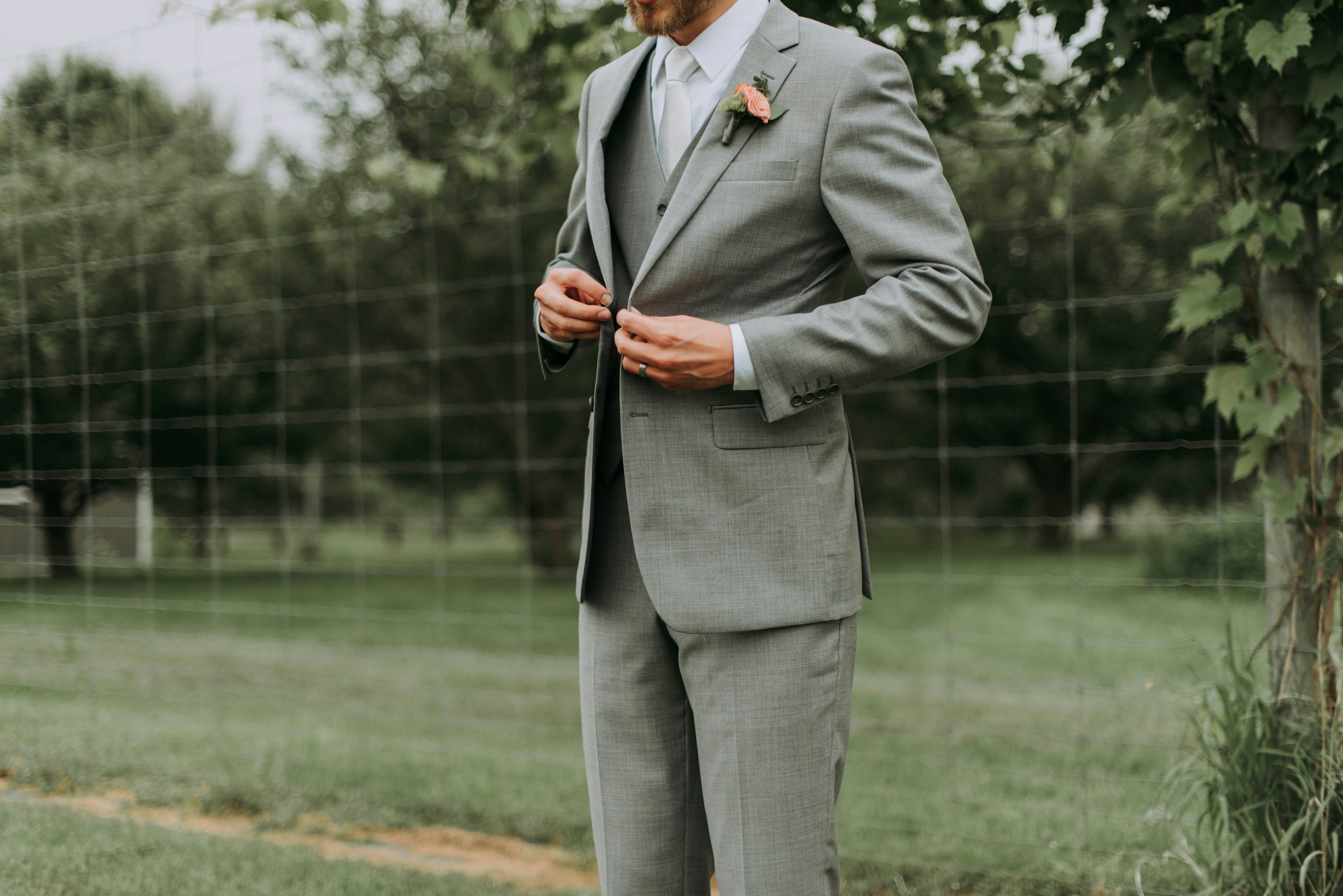 Gros plan sur un marié qui ajuste le bouton de sa veste | Source : Unsplash