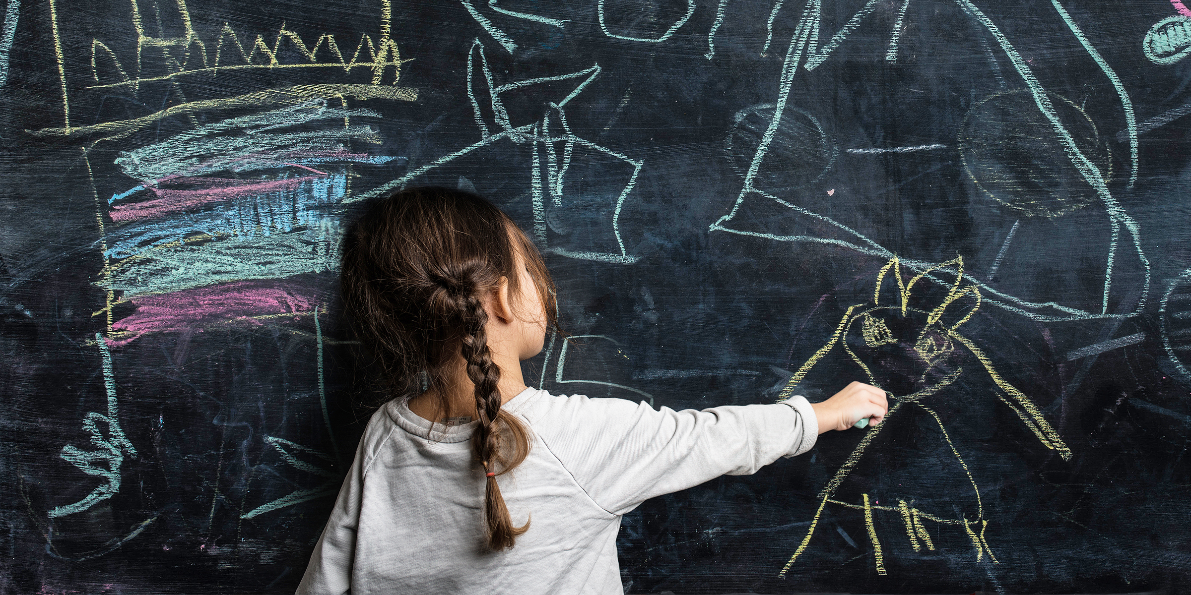 Petite fille écrivant sur un tableau noir | Source : Getty Images
