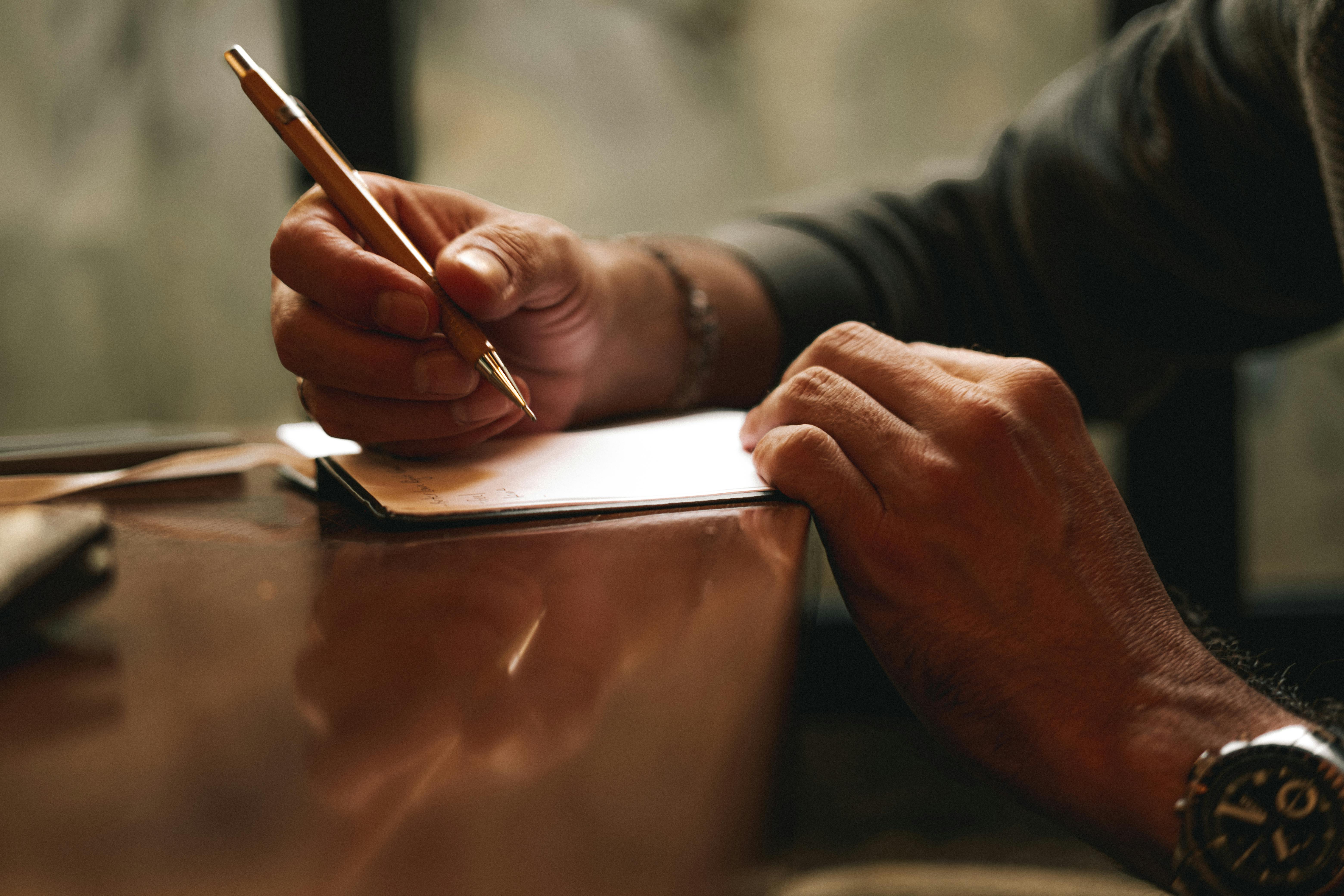 Une personne qui écrit sur une feuille de papier | Source : Pexels
