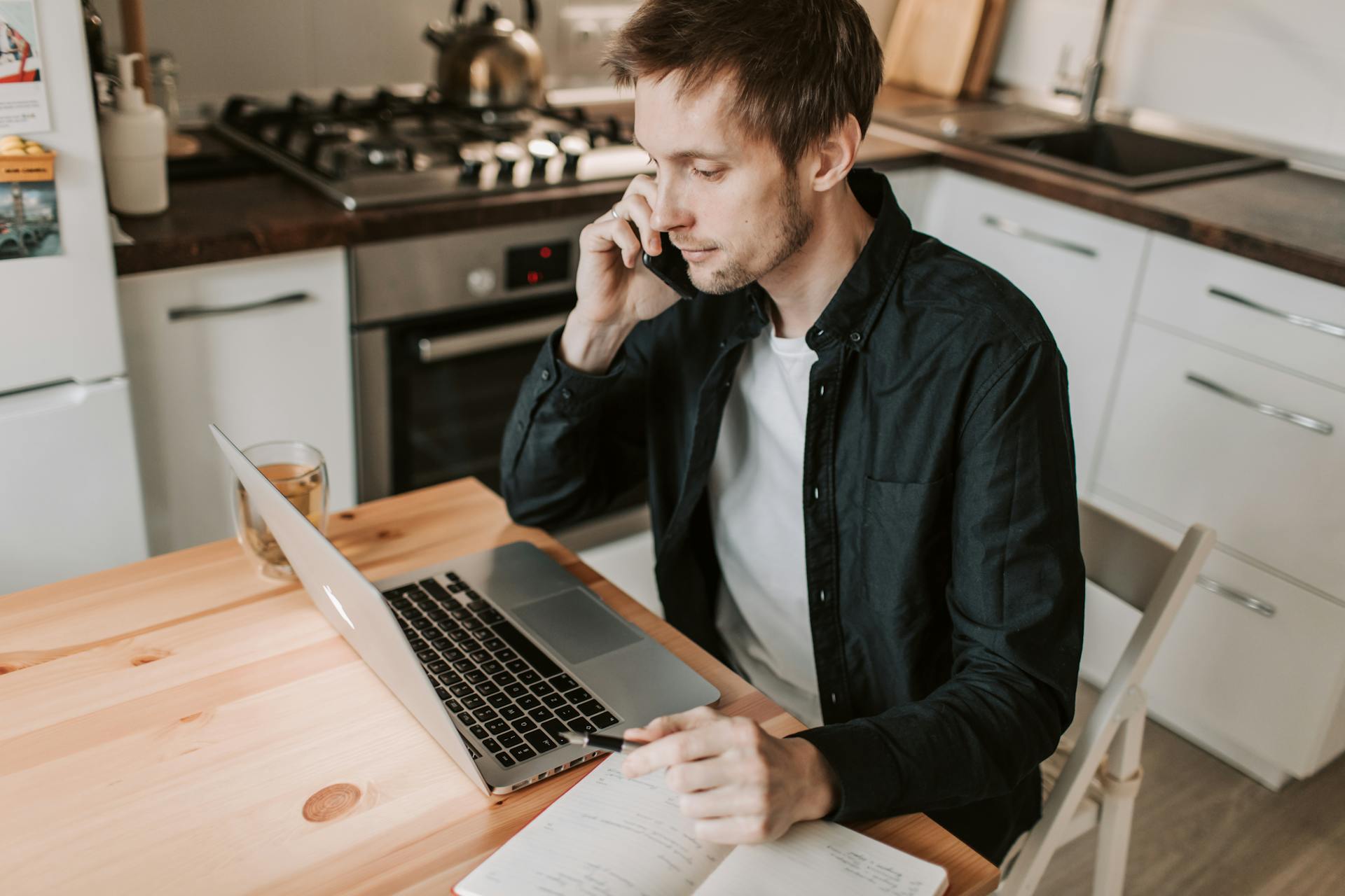 Un homme assis à une table de cuisine en train de passer un appel téléphonique | Source : Pexels