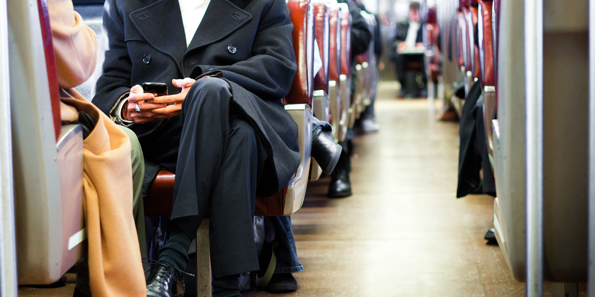 Un homme en costume assis dans un train très fréquenté | Source : Shutterstock