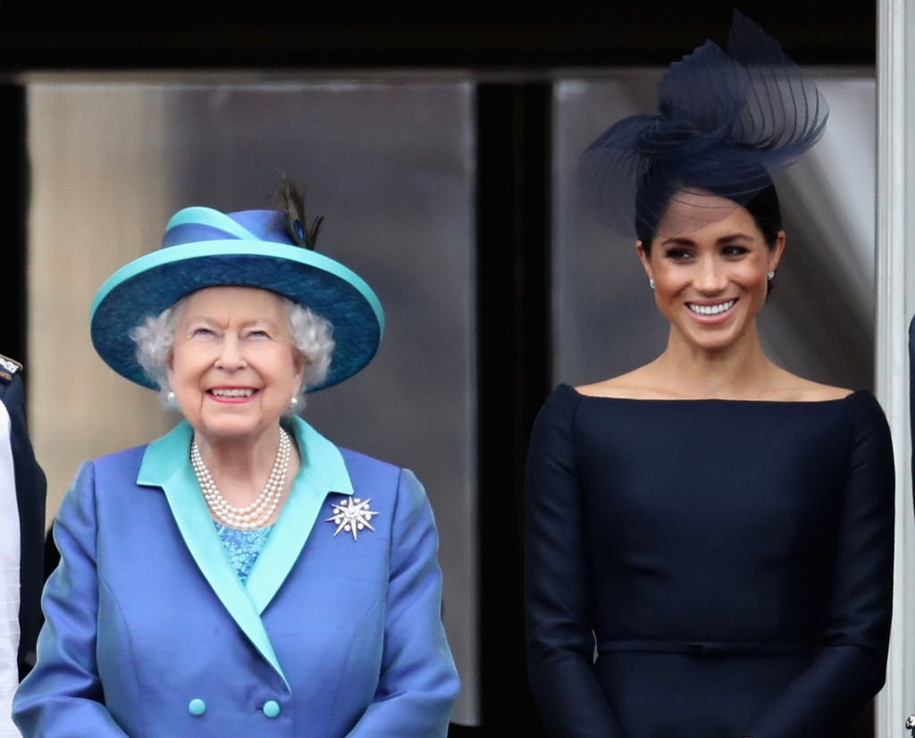 La reine Elizabeth II et Meghan, duchesse de Sussex, observent le défilé aérien de la RAF sur le balcon du palais de Buckingham, alors que des membres de la famille royale assistent aux événements marquant le centenaire de la RAF | Photo : Getty Images