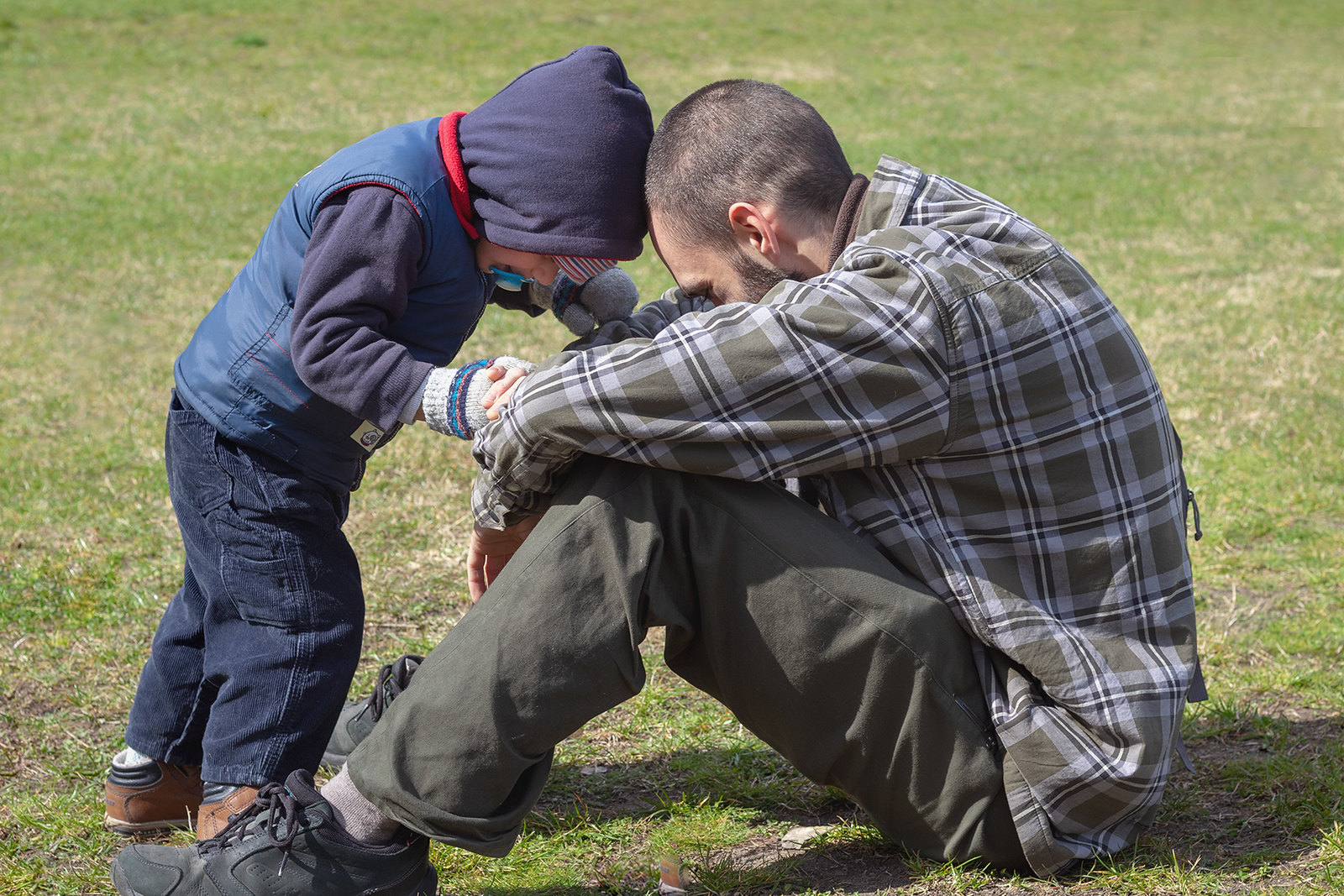 Un père et son fils assis sur un terrain herbeux | Source : Flickr