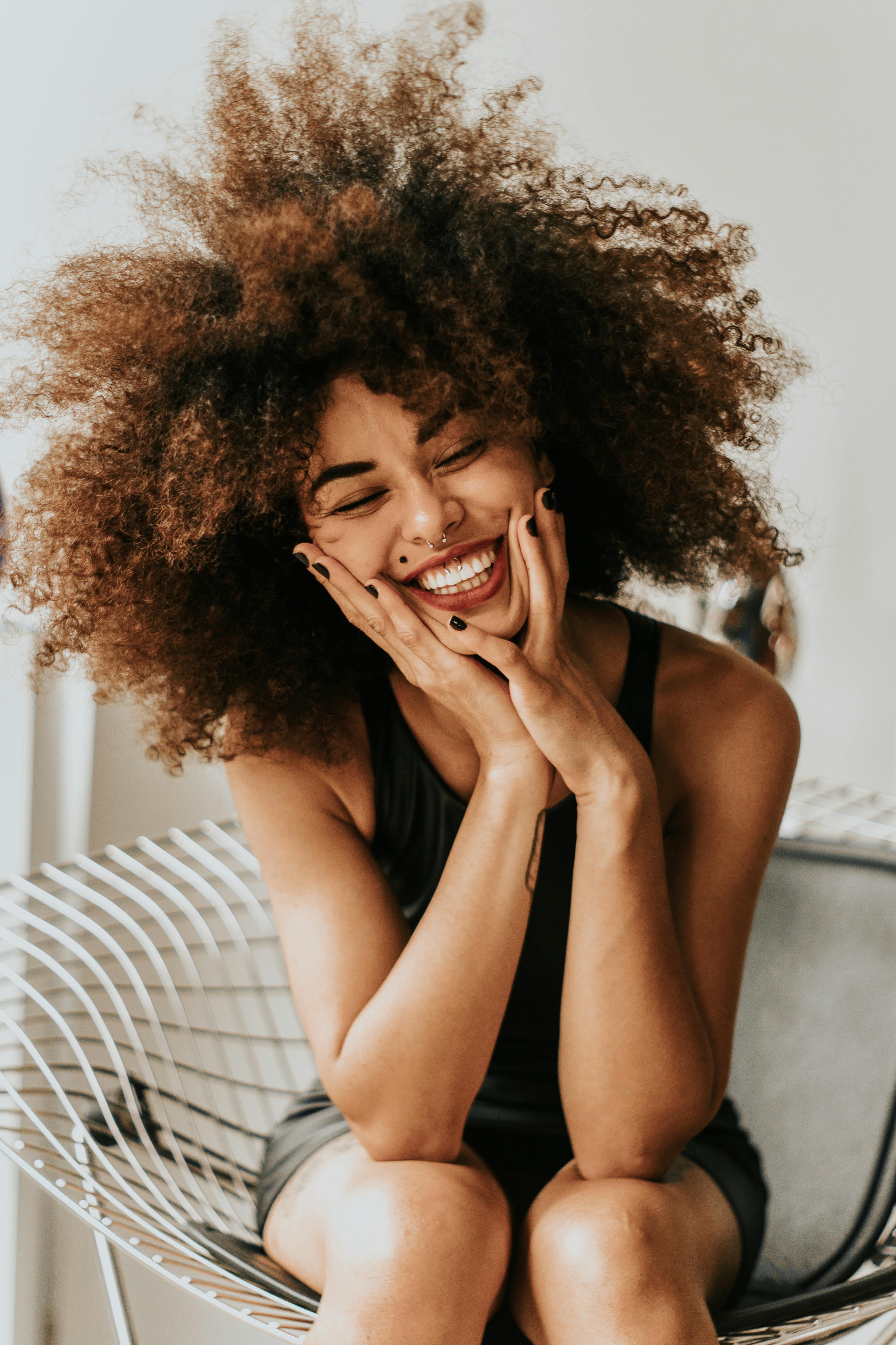 Une femme excitée et souriante qui tient son visage | Source : Pexels