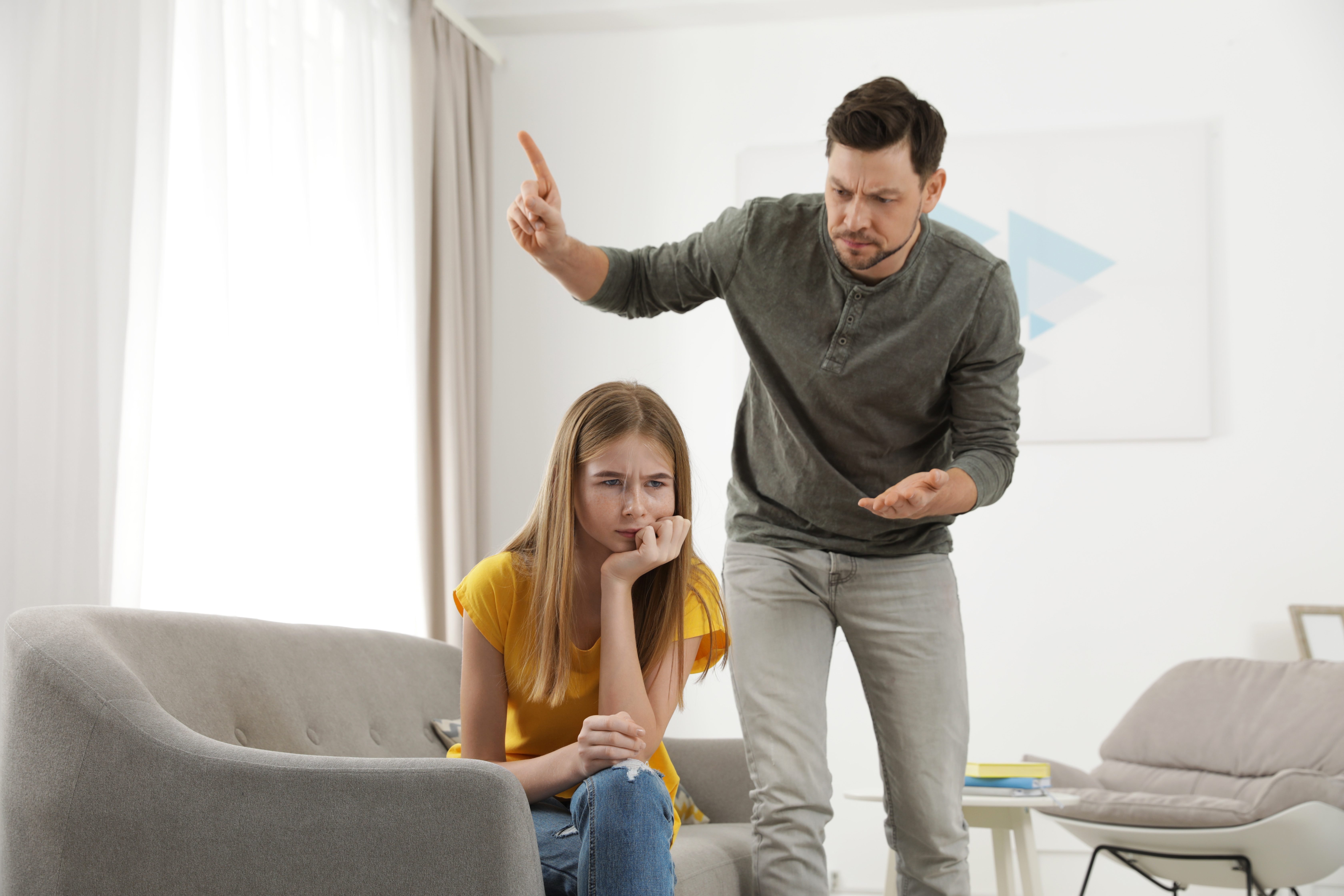 Un homme grondant une fille dans un salon | Source : Shutterstock