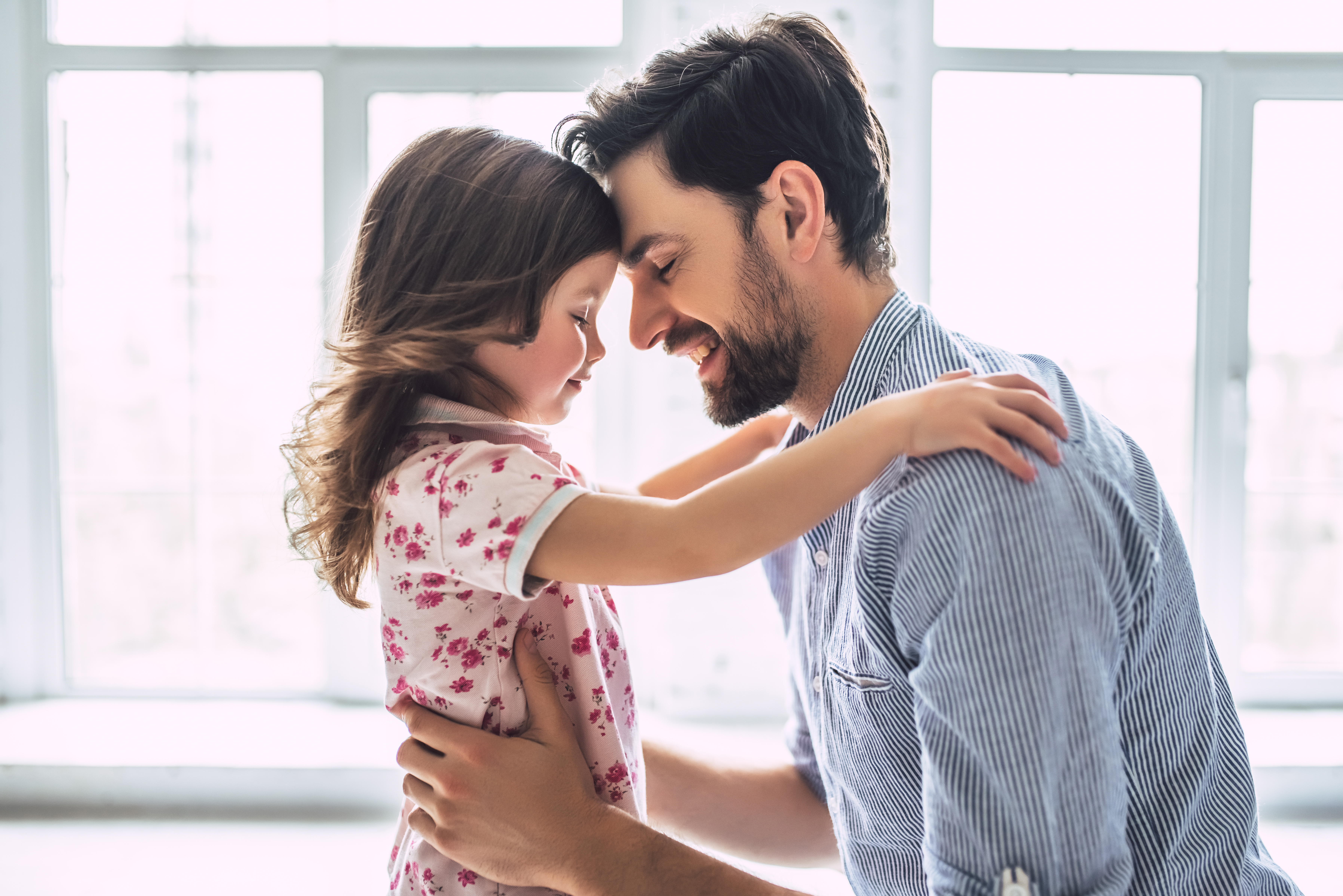 Un père et sa fille s'embrassent amoureusement les yeux fermés. | Source : Shutterstock