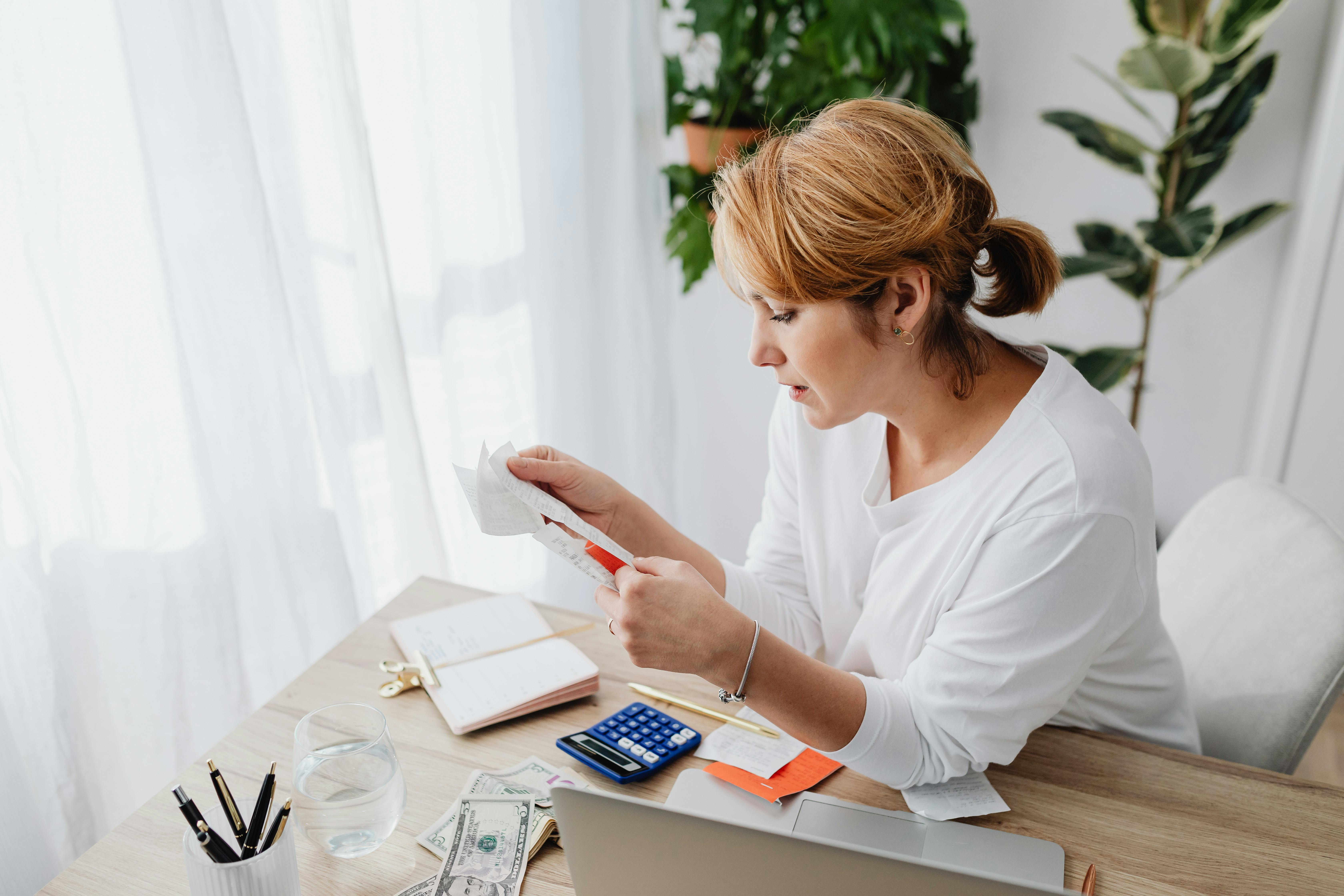 Une femme regarde un morceau de papier sur un bureau | Source : Pexels