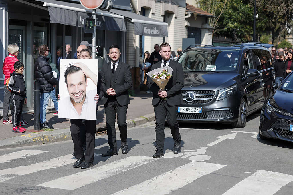 Une photo de Bruno Salomone est portée en tête du cortège, devant le corbillard, lors du trajet vers le cimetière à l'occasion des funérailles de Bruno Salomone, le 23 mars 2026 à Joinville-le-Pont, en France I Source : Getty Images