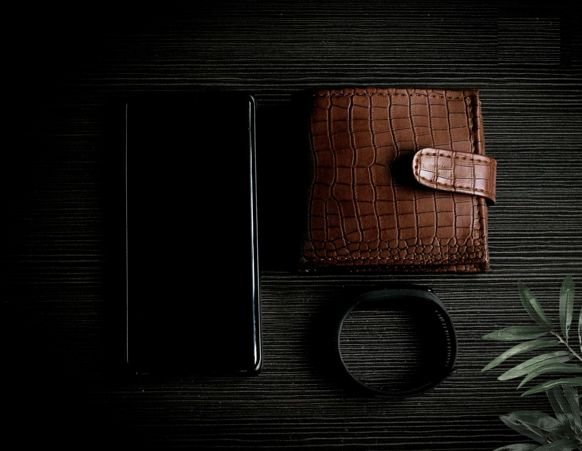 Un portefeuille, un téléphone et un bracelet sur une table | Source : Pexels