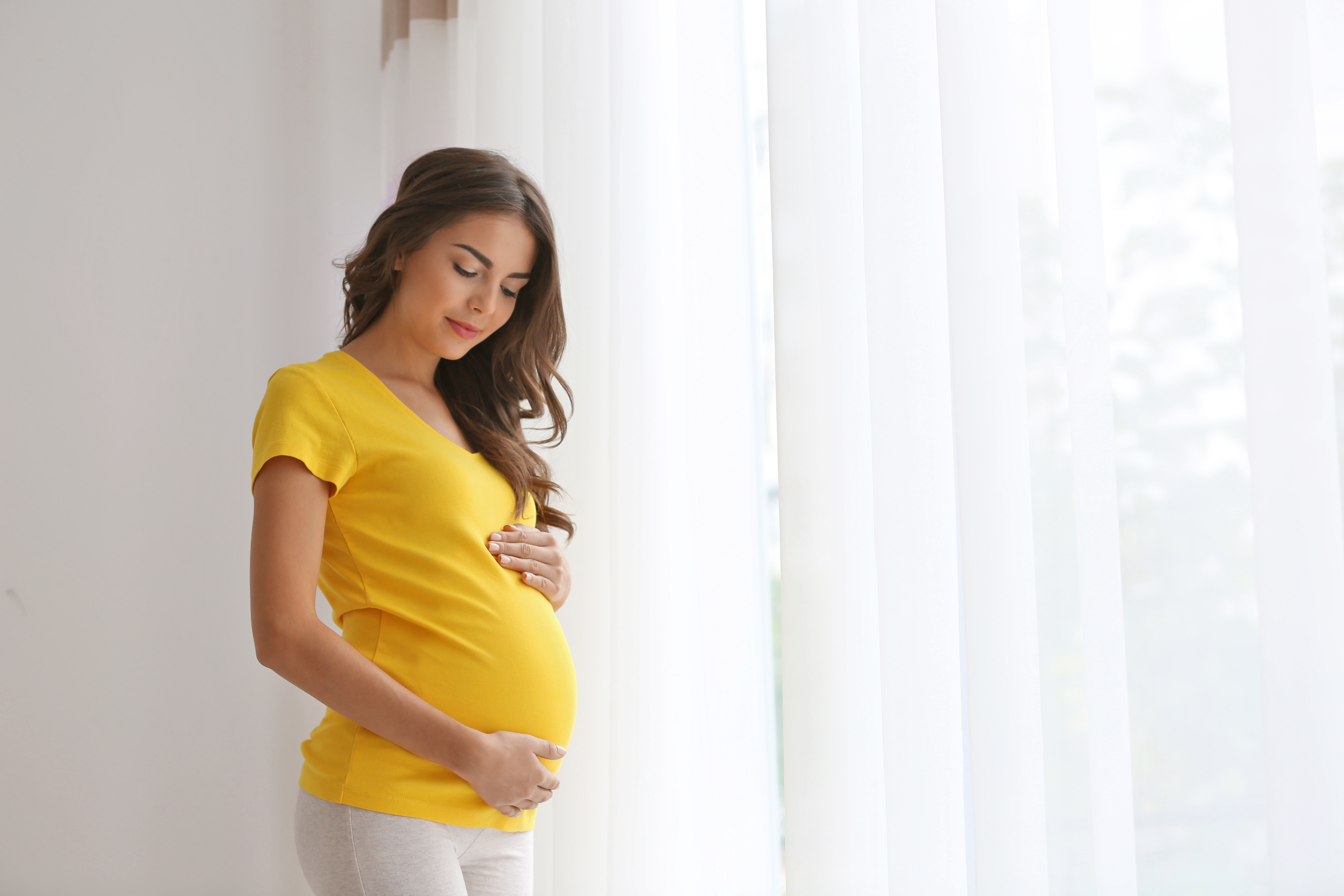 Une jeune femme enceinte se tenant le ventre | Source : Shutterstock