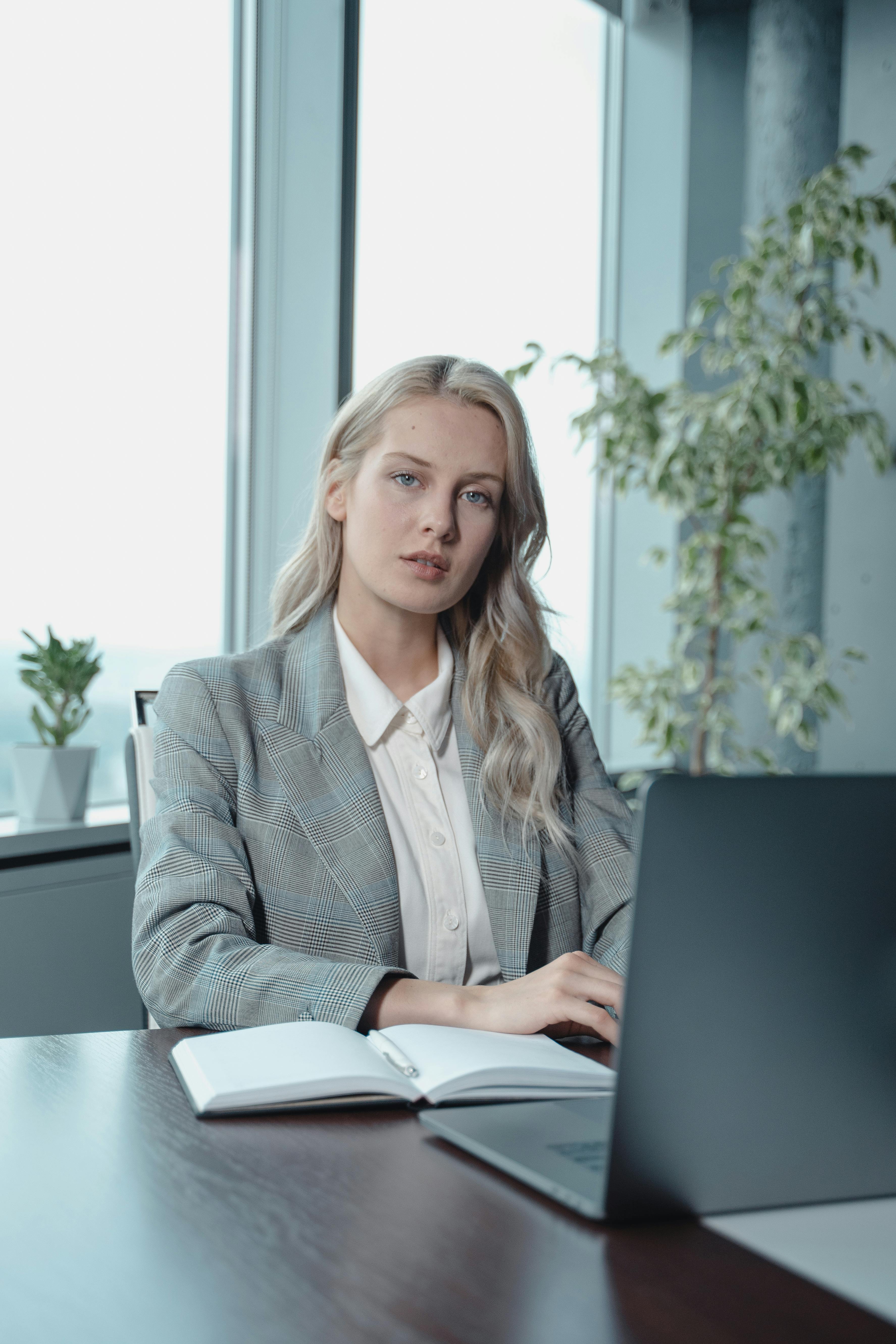 Femme en blazer gris assise près de la table avec un ordinateur portable | Source : Pexels