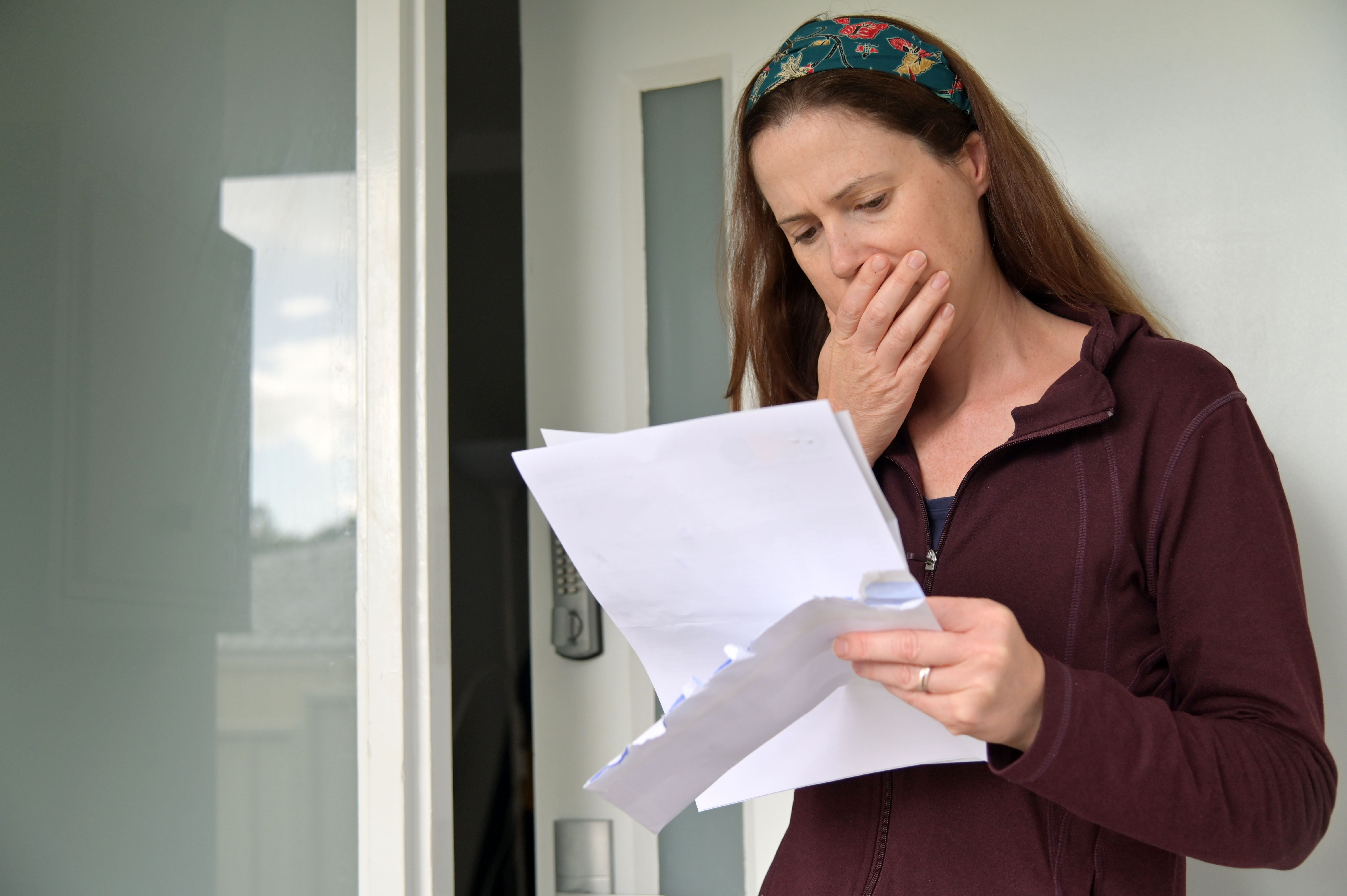 Una mujer leyendo un documento con una mano en la boca | Fuente: Shutterstock