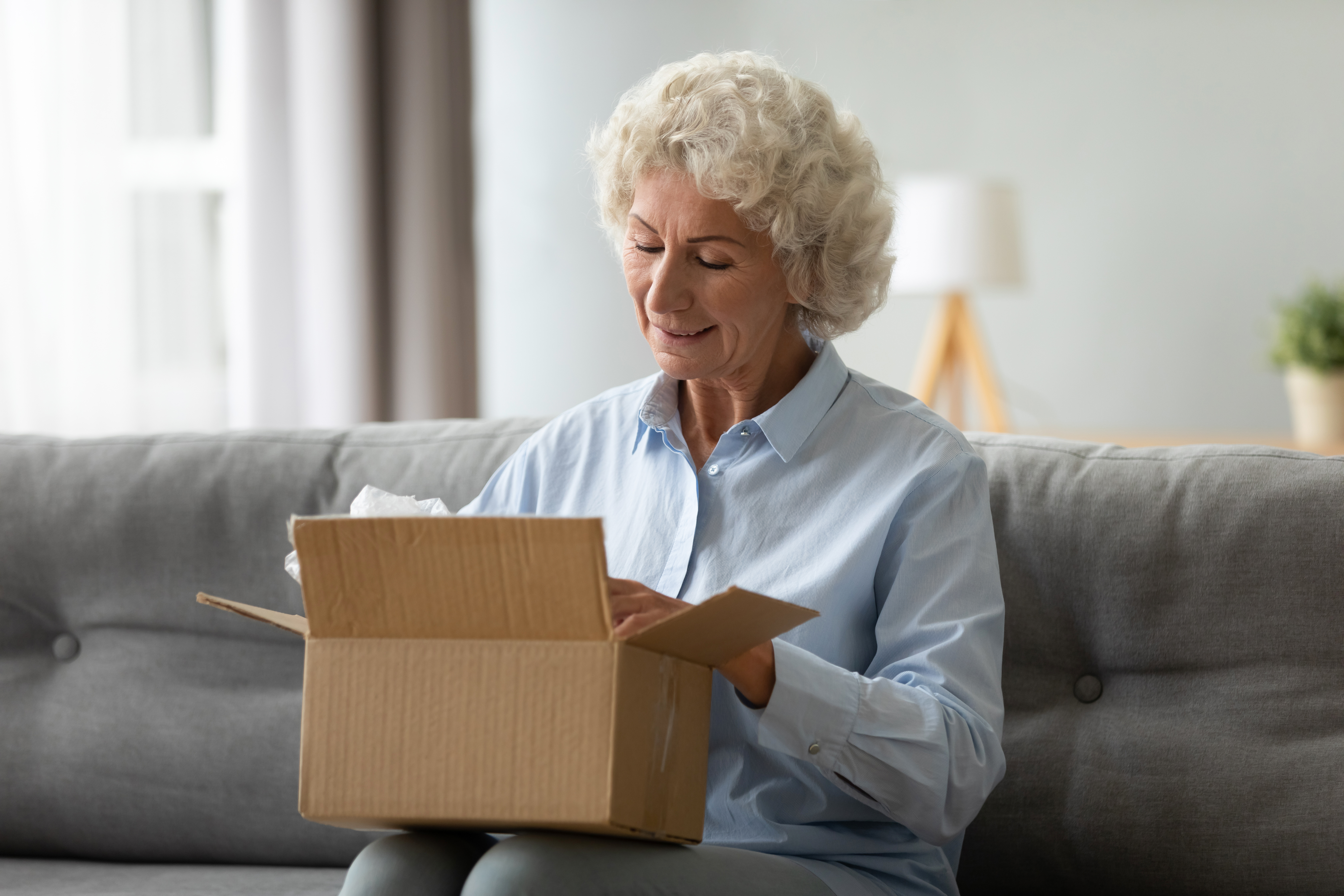 Une cliente âgée et souriante reçoit un colis postal à son domicile | Source : Getty Images