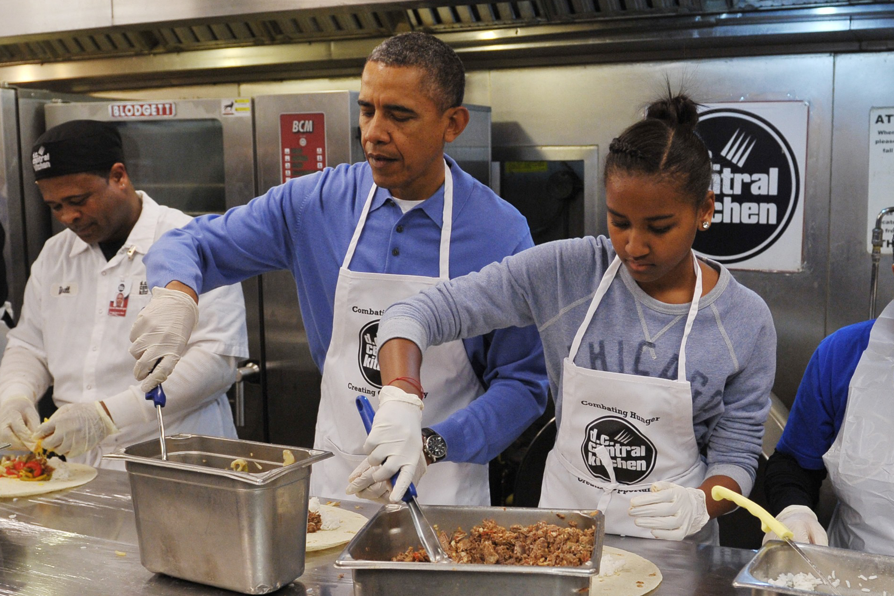 Barack et Sasha Obama participant à un projet de service communautaire, en préparant des burritos à l'occasion de la journée Martin Luther King Jr à Washington, le 20 janvier 2014. | Source : Getty Images